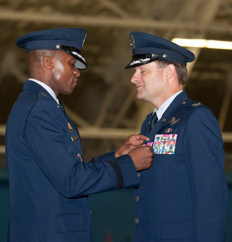 Maj. Gen. Darren W. McDew, Air Force District of Washington commander, presents Col. Ken Rizer, 11th Wing/Joint Base Andrews commander, with the Legion of Merit award during the 11th Wing Change of Command ceremony held in Hangar 3 here July 6. (Photo/Bobby Jones)