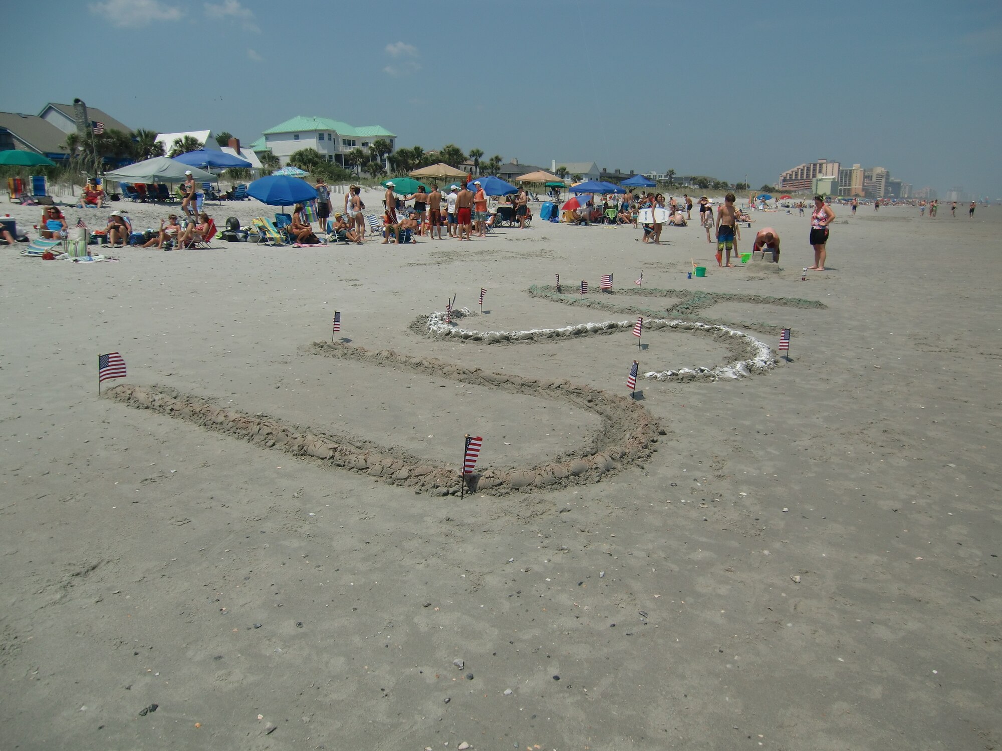 “USA” is written and colored in the sand so it can be visible to the formation of F-16 Fighting Falcons from the 20th Fighter Wing’s 79th Fighter Squadron “Flying Tigers” who flew down the South Carolina coastline as part of Salute from the Shore July 4, 2012. Patriotic displays lined the beach as beachgoers came to show their support of the United States and its service members. (U.S. Air Force photo by 2nd Lt. Earon Brown/Released)