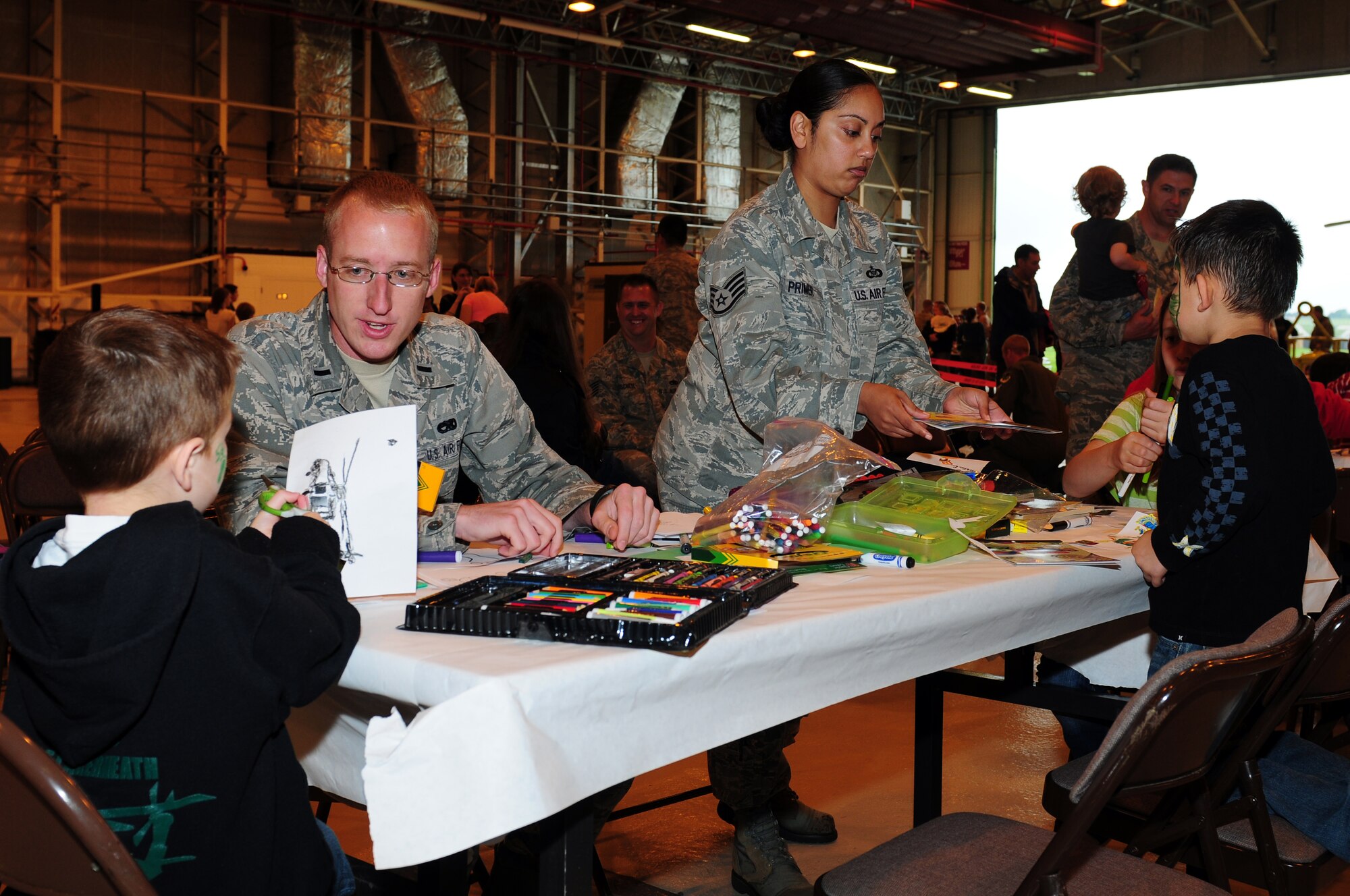 ROYAL AIR FORCE LAKENHEATH, England – 1st Lt. Alexander Clift, 56th Maintenance Unit officer in charge, and Staff Sgt. Candice Primer, 56th Rescue Squadron aviation resource management, color with children during the 56th RQS spouses’ day July 6, 2012. The 56th RQS hosted a day at the squadron featuring incentive flights for more than 50 family members as well as jumping castles and coloring activities for children. (U.S. Air Force photo by Airman 1st Class Cory D. Payne)