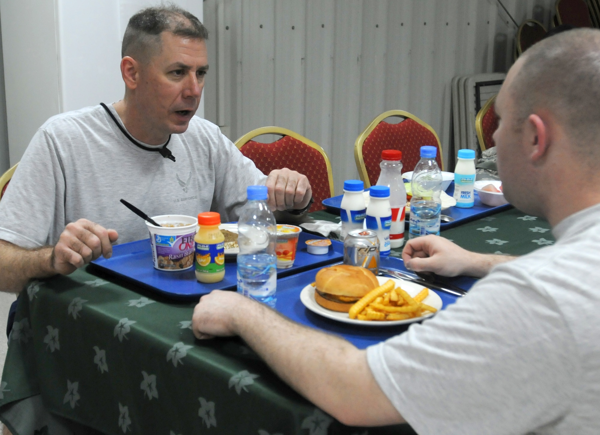 SOUTHWEST ASIA - U.S. Air Force Chief Master Sgt. William Ford, 380th Expeditionary Operations Group superintendent, talks over lunch with his son, Senior Airman Michael Ford, 970th Expeditionary Airborne Air Control Squadron computer display maintenance technician, in a dining facility July 7, 2012. The father and son have been deployed here since April, which marks the first time the two have been working at the same location. (U.S. Air Force photo/Tech. Sgt. Amanda Savannah)