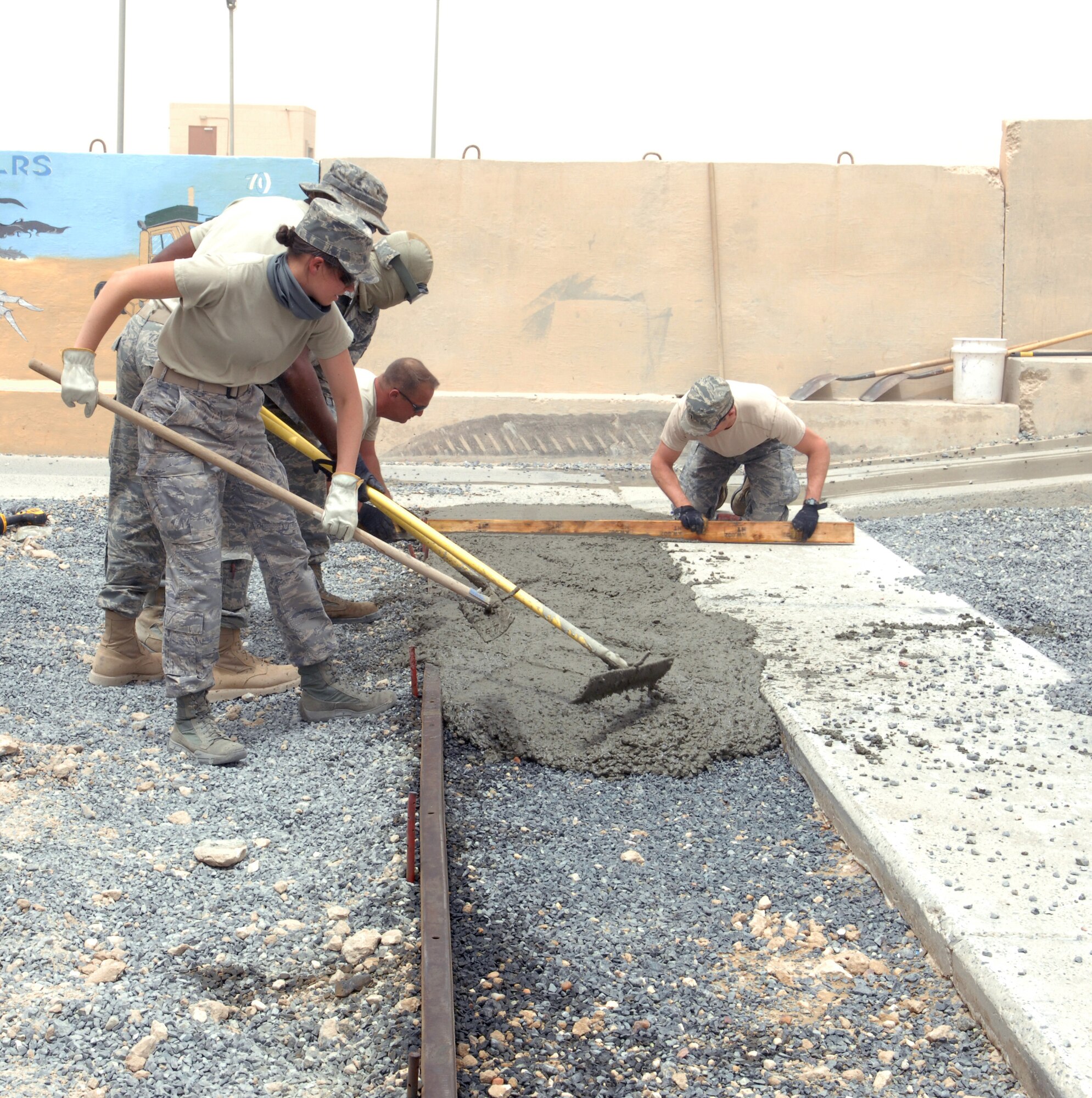SOUTHWEST ASIA – – Members of the 386th Expeditionary Civil Engineer Squadron, smoothes freshly-poured cement to widen the sidewalk from the exit door of the dining facility here July 7. (U.S. Air Force photo/Staff Sgt. Alexandra M. Boutte) 
