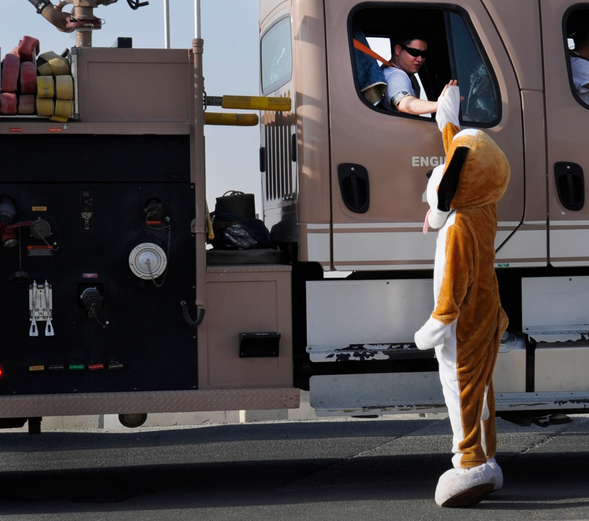 SOUTHWEST ASIA – Senior Airman Jack McLauglin, 386th Expeditionary Civil Engineer Squadron firefighter, gives the 386th Air Expeditionary Wing’s mascot a high-five before the parade during the Freedom Fest 2012 here July 4. The festival consisted of several events including a Humvee push, ping-pong, billiards, cornhole, video game tournaments, swimming races, tug-o-war and a watermelon eating contest.  (U.S. Air Force photo/Staff Sgt. Alexandra M. Boutte)