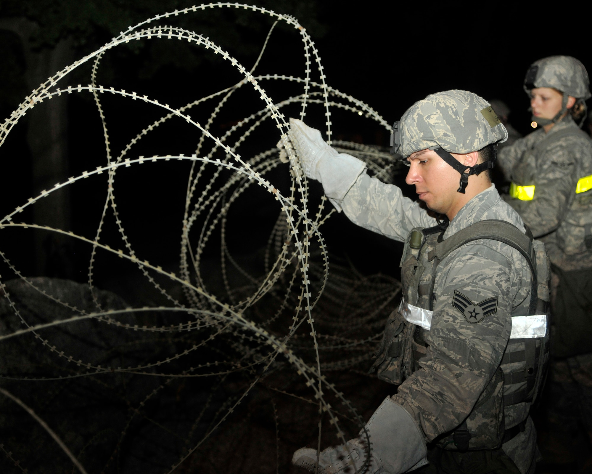 Airmen from the 8th Security Forces Squadron place concertina-wire around the perimeter of the 8th Fighter Wing headquarters building at Kunsan Air Base, Republic of Korea, July 8, 2012. This is the first exercise of the summer for Kunsan since the unit compliance inspection in April. (U.S. Air Force photo/Senior Airman Marcus Morris)