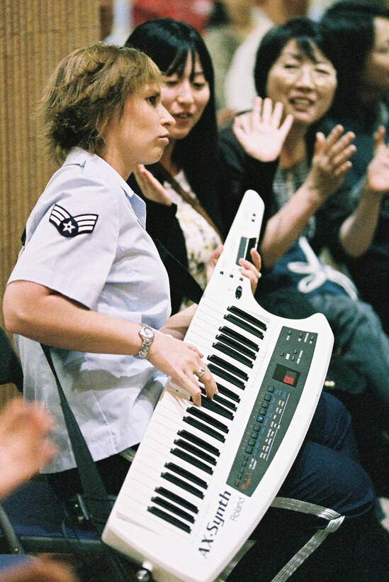 MUTSU CITY, Japan -- Senior Airman Michelle Hooper, Band of the Air Force Reserve keyboardist, shares a seat with the audience during the conclusion of the bands performance at the Mutsu Kasamaeka Facility, Japan, June 4, 2012. Hooper played keytar on several tunes which allowed her mobility. (U.S. Air Force photo/Staff Sgt. Josh Voyles)