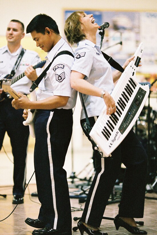 MUTSU CITY, Japan -- Staff Sgt. Daniel Santos, Band of the Pacific-Asia guitarist, and Senior Airman Michelle Hooper, Band of the Air Force Reserve keyboardist, solo back to back on The Eagles' "Hotel California" at the Mutsu Kasamaeka Facility, Japan, June 4, 2012. Hooper accompanied Santos on keytar many times during the show. (U.S. Air Force photo/Staff Sgt. Josh Voyles)