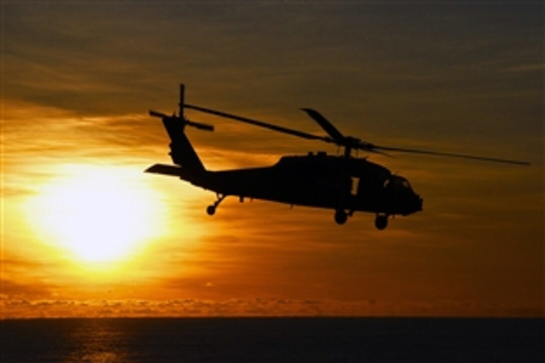 An MH-60S Sea Hawk helicopter approaches USNS Amelia Earhart at sunrise in the Pacific Ocean, July 8, 2012, after delivering supplies to the aircraft carrier USS George Washington during a vertical replenishment mission.
