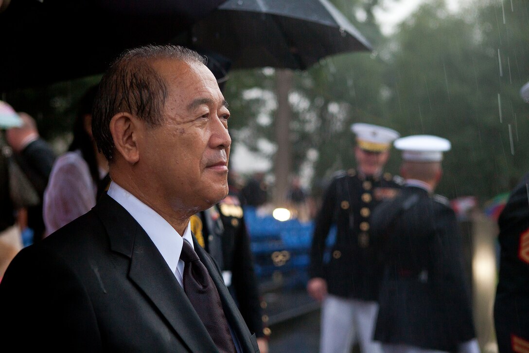 Ambassador of Japan to the United States Ichiro Fujisaki, stands in the rain at the conclusion of a Tuesday Sunset Parade at the Marine Corps War Memorial in Arlington, Va., July 10. Fujisaki, the guest of honor of the parade, along Marines and guests remained at the parade even after inclement weather cut short the ceremony.