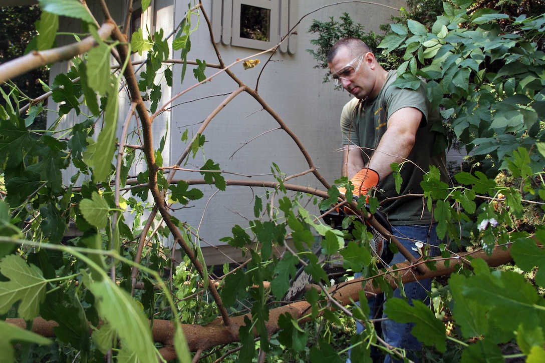 Recruiting Substation Burnsville's Sgt. Joshua A. Draveling, 27, from Milwaukee, saws limbs from a fallen tree on July 11. Draveling and several aspiring Marines from RSS Burnsville recently spent their weekend removing debris after a thunderstorm knocked down several trees, causing thousands of dollar of damage.