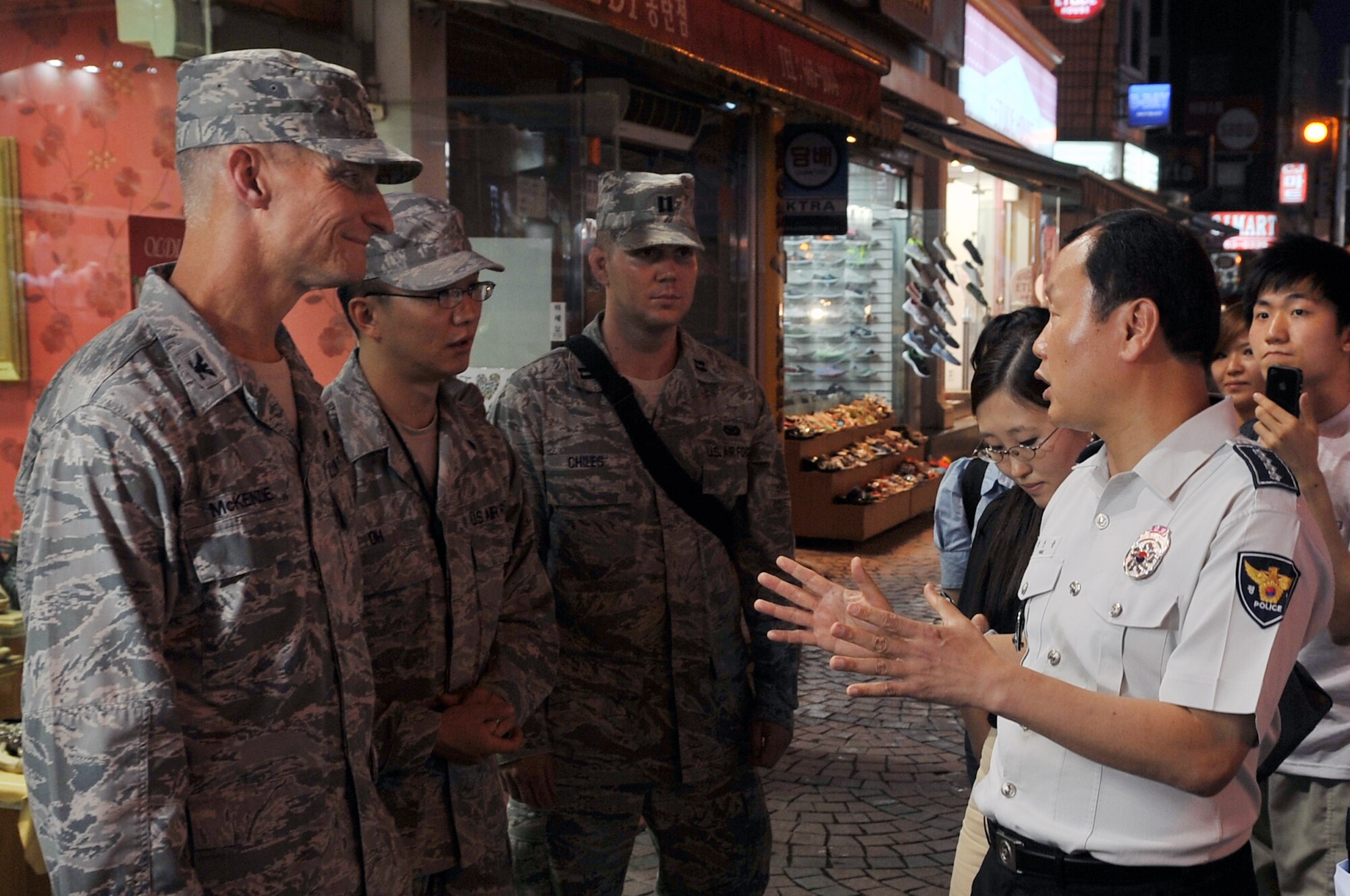 Mr. Sang Yung Pak, Chief of Pyeongtaek Police, describes Korean National Police authority with Col. Patrick McKenzie (left), 51st Fighter Wing commander, Staff Sgt. Daniel Oh, 51st Medical Group independent duty medical technician, and Capt. Cody Chiles, 51st FW Public Affairs, during a joint town patrol in the Songtan Entertainment District July 10, 2012. Base officials and Korean National Police conducted a joint town patrol in Songtan as a way to strengthen the ROK and United States alliance. The patrol also highlighted the importance of joint partnership in law enforcement and force protection. (U.S. Air Force photo/Staff Sgt. Craig Cisek)