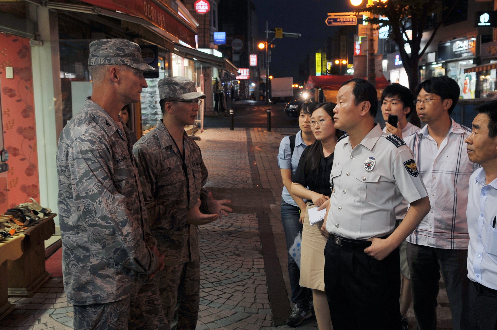 Col. Patrick McKenzie, 51st Fighter Wing commander, listens as Staff Sgt. Daniel Oh, 51st Medical Group independent duty medical technician, translates to city officials July 10, 2012, during a joint town patrol in Songtan Entertainment District, Pyeongtaek, Republic of Korea. Joint town patrols strengthen the alliance between the ROK and United States. The patrol also highlighted the importance of joint partnership. (U.S. Air Force photo/Staff Sgt. Craig Cisek)