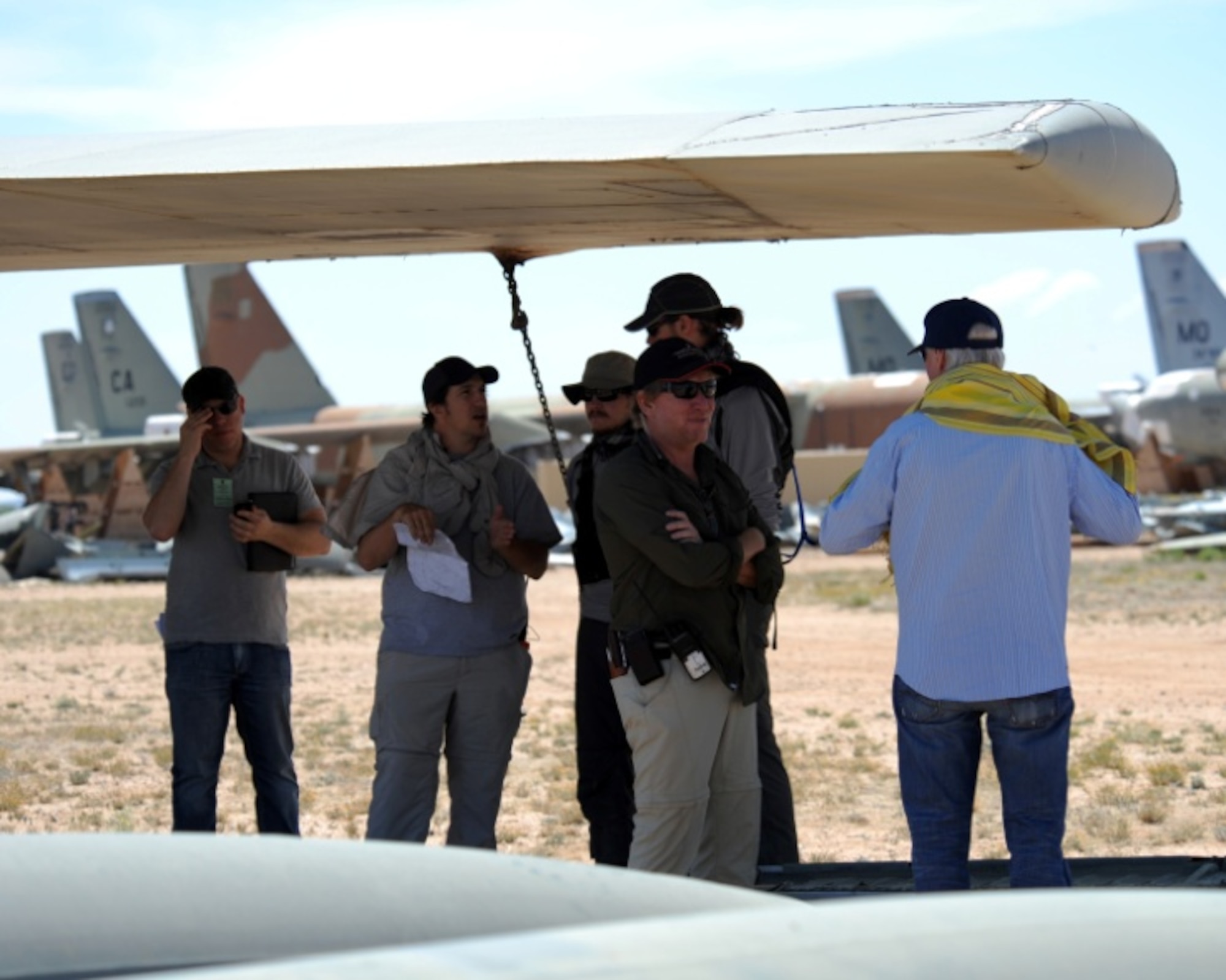 Members of “The Great Escape” production team use an aircraft wing for shade at the 309th Aerospace Maintenance and Regeneration Group on Davis-Monthan Air Force Base, Ariz., May 10, 2012. Three two-person teams competed to complete tasks for a chance to win $100,000. (U.S. Air Force photo by Airman 1st Class Timothy D. Moore/Released)