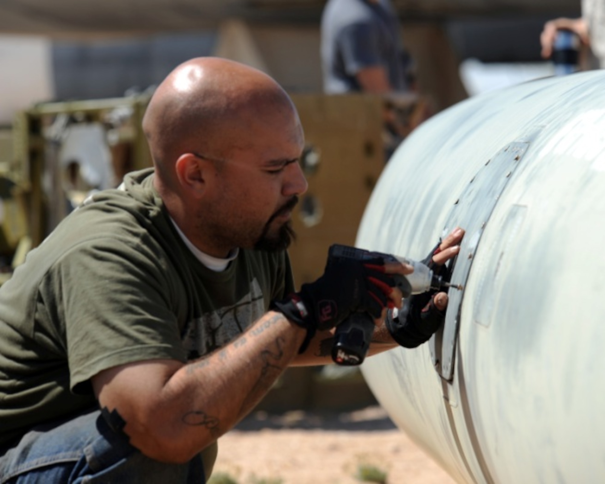 Alex Horton, “The Great Escape” art department swingman, unscrews a safety hatch on a fuel tank in the airplane graveyard of the 309th Aerospace Maintenance and Regeneration Group on Davis-Monthan Air Force Base, Ariz., May 10, 2012. The Great Escape used the “Boneyard” as the setting for one of its shows. (U.S. Air Force photo by Airman 1st Class Timothy D. Moore/Released)