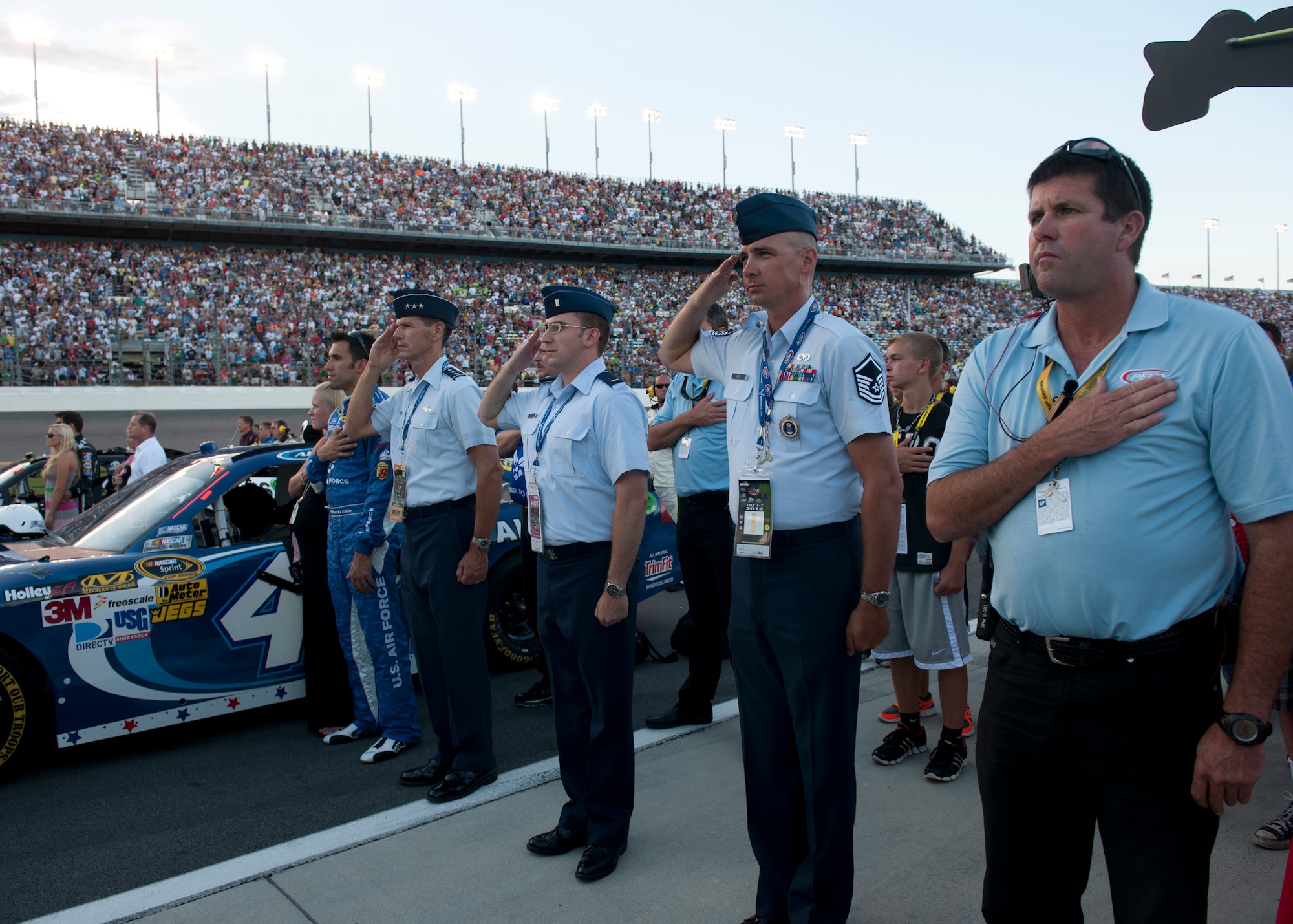 U.S. Air Force Lt. Gen. Stanley Clarke, Continental U.S. North American Aerospace Defense Command Region -- 1st Air Force (Air Forces Northern) commander, presents arms during the playing of the national anthem, along with NASCAR driver Aric Almirola , 2nd Lt. Roberto Carbonell, Air Combat Command (Air Forces Northern) commander's executive, and Master Sgt. Brad Barth, 336th Recruiting Squadron marketing NCO, July 7, 2012, at the Daytona International Speedway, Daytona, Fla. Clarke administered the Oath of Enlistment to members of the Delayed Entry Program and toured the area prior to the race. (U.S. Air Force photo by Senior Airman Eileen Meier/Released)