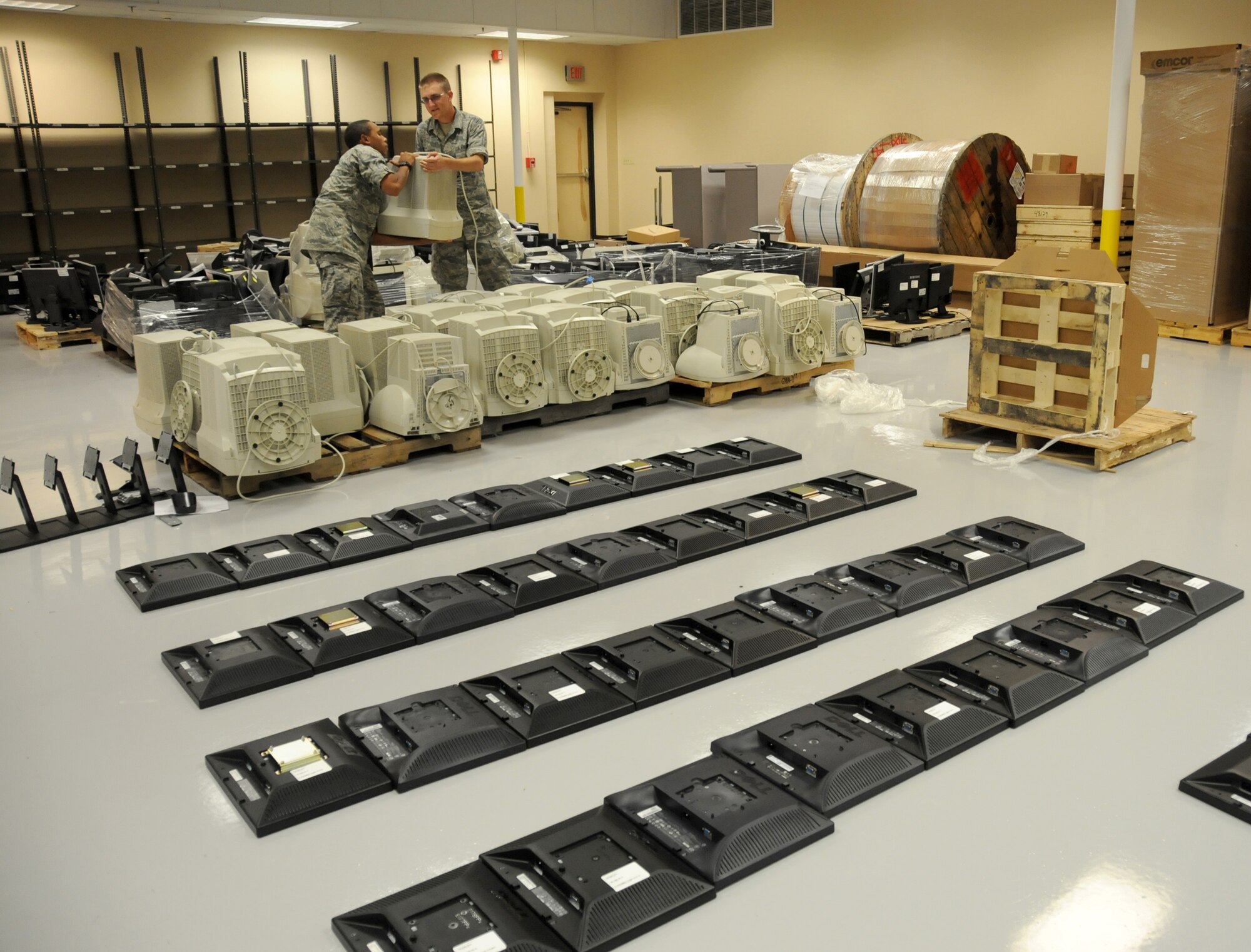 Airmen Basic Daniel Rodriguez and Robert Alvies, 338th Training Squadron, place large computer monitors onto crates for transporting at the Locker House June 27, 2012, at Keesler Air Force Base, Miss. The monitor turn in is part of a program started by the 81st Communications Squadron  Management information technology section to rid the base of excess IT assets.  A total of 1200 plus monitors where turned in and transferred to other equipment custodians to be used in their squadrons or donated to local schools. (U.S. Air Force photo by Kemberly Groue)