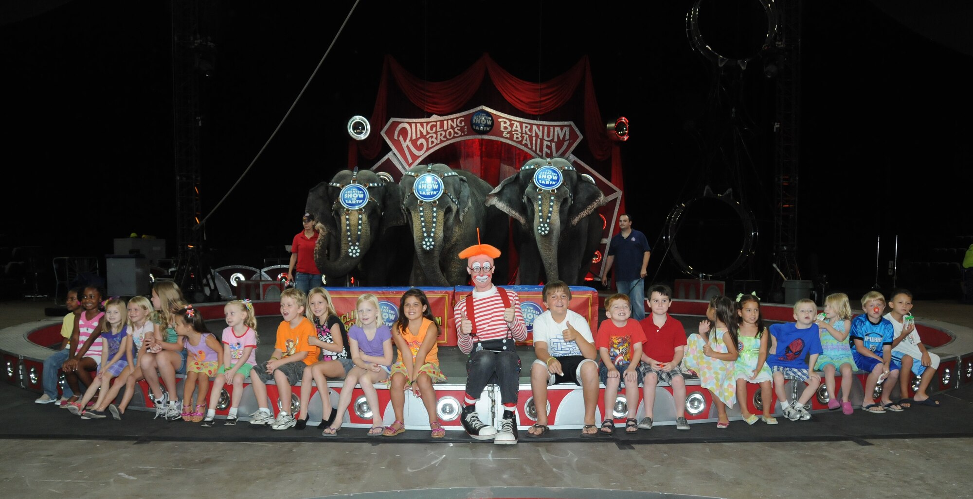 Dean the Clown, a member of the Ringling Brothers and Barnum and Bailey Circus, poses for a group photo with children of deployed troops from Keesler Air Force Base, Miss ., at the Mississippi Coast Coliseum July 5, 2012. The circus invited the children to learn about circus style exercises and received healthy eating tips that their elephants follow. They also received free tickets to the show.  (U.S. Air Force photo by Kemberly Groue)