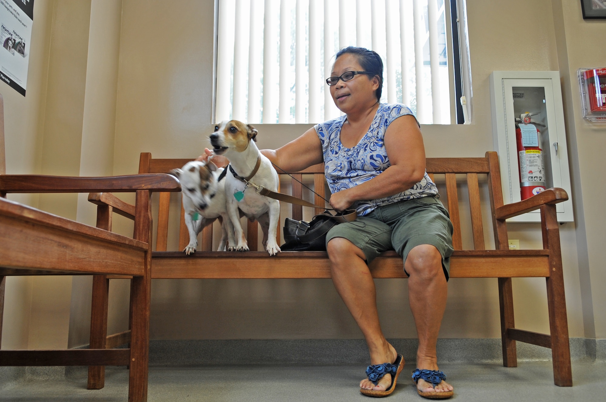 Rosa McCabe attempts to calm her dogs Betty and Crocker while they wait to be seen at the Veterinary Treatment Facility on Seymour Johnson Air Force Base, N.C., July 10, 2012. The clinic offers various vaccinations, tests and exams for cats and dogs of Department of Defense identification card holders. (U.S. Air Force photo/Airman 1st Class Aubrey Robinson/Released)