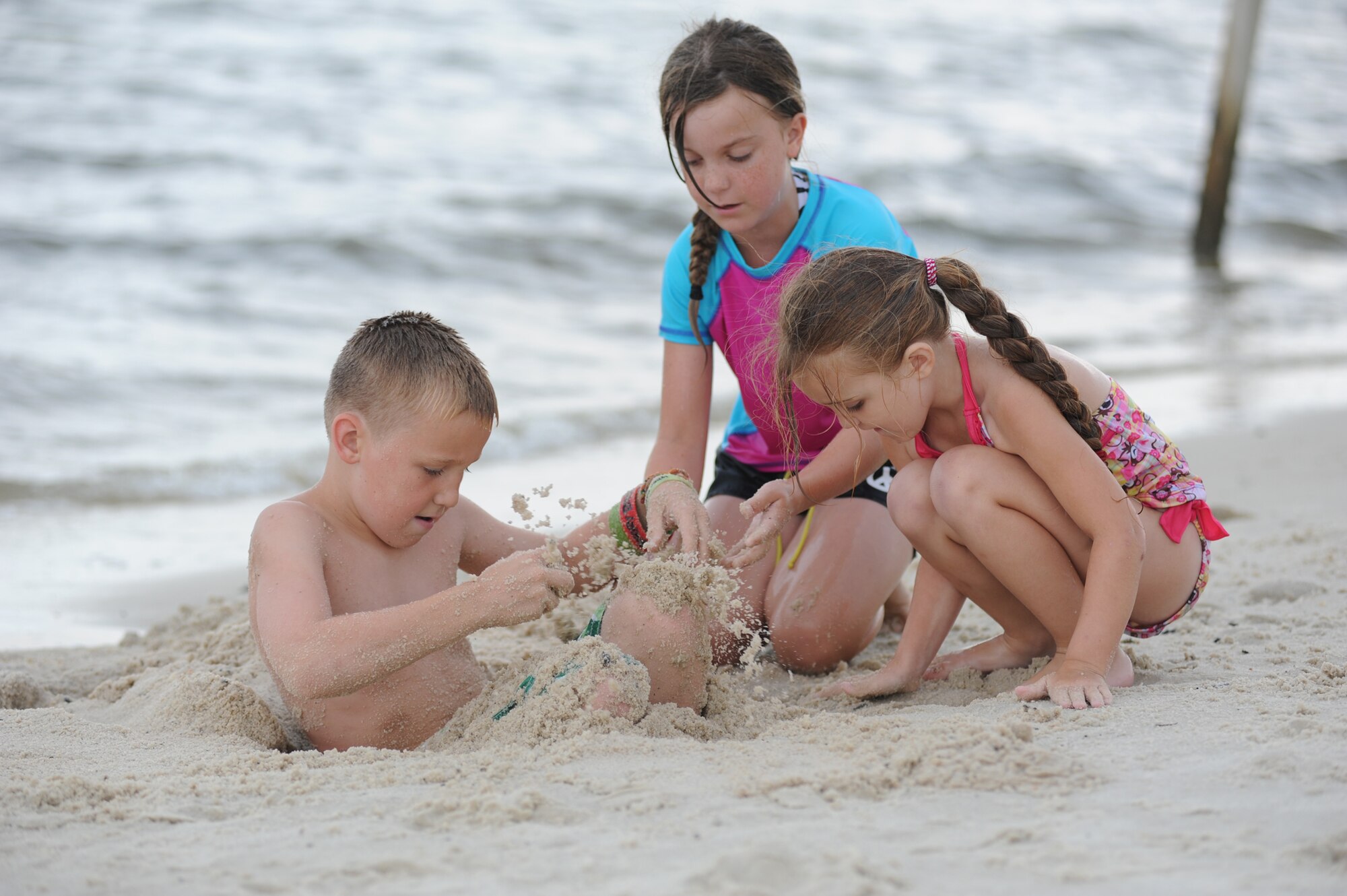 A.J. Wright, 10, Lauren McLemore, 9, and Maddie Wright, 5, work together to bury A.J. in the sand at the independence day Beach Bash in Biloxi, Miss., July 4, 2012.  The event included Games, music, food, fireworks, contests and prizes.  A.J. and Maddie’s parents are Lisa and Lt. Col. Jonathan Wright, 81st Mission Support Group deputy commander.  Lauren’s parents are Jo and Lt. Col. Jeffrey McLemore, 334th Training Squadron commander.  (U.S. Air Force photo by Kemberly Groue)