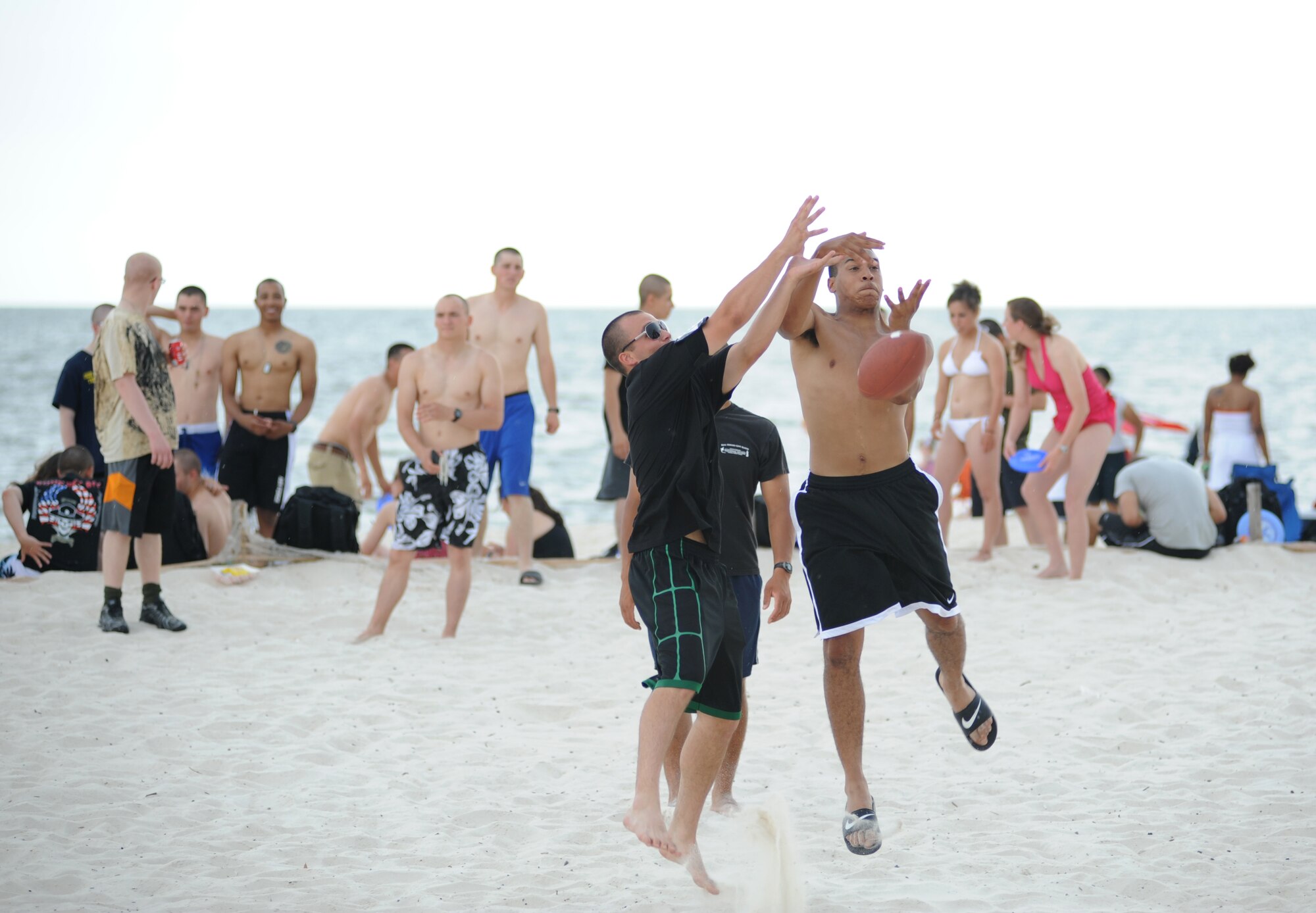 Airman 1st Class Kaleb Booth and Airman Basic George McInnis, 334th Training Squadron, leap into the air to catch a football at the independence day Beach Bash in Biloxi, Miss., July 4, 2012.  The event included Games, music, food, fireworks, contests and prizes.  (U.S. Air Force photo by Kemberly Groue)