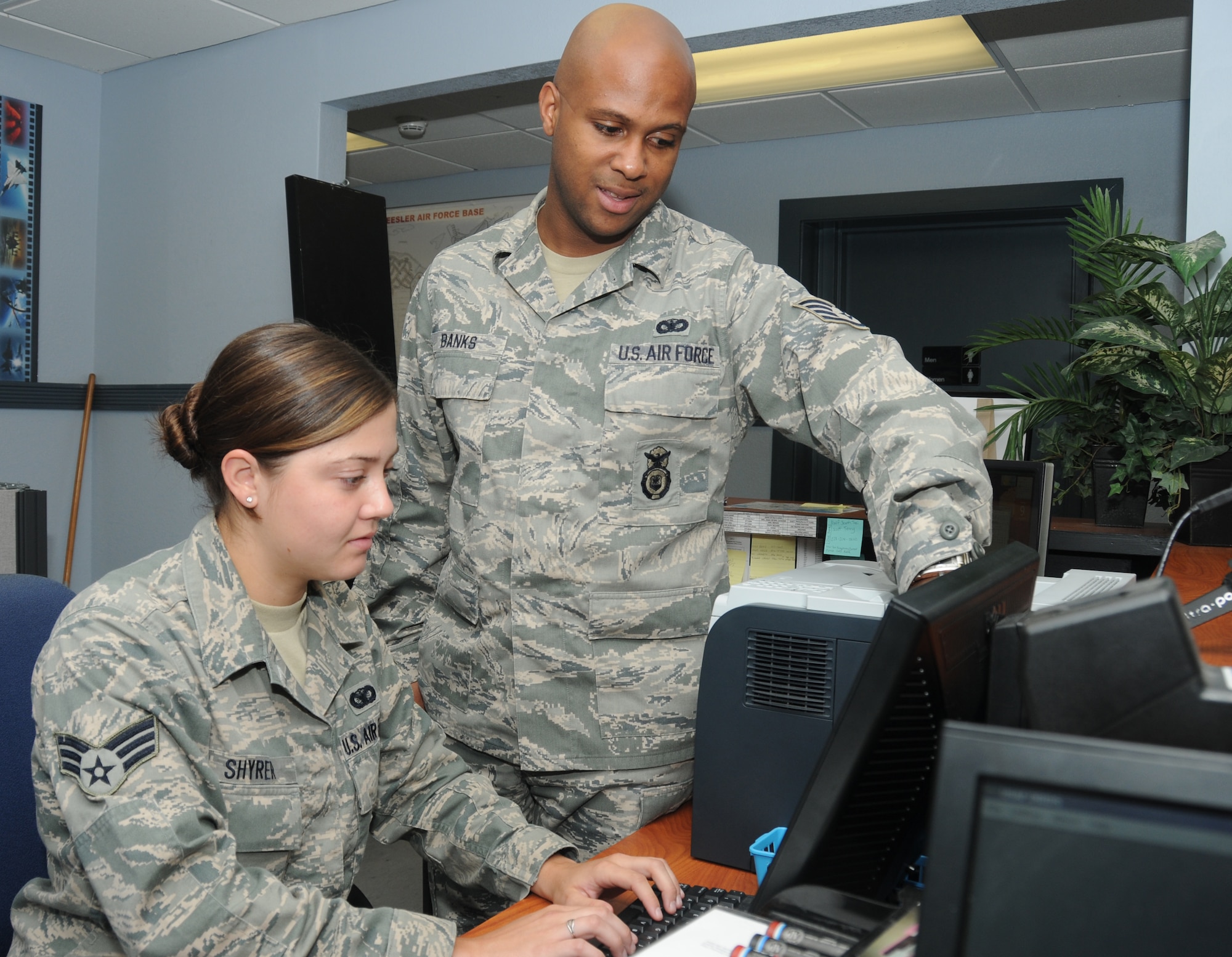 Senior Airman Brianna Shyrer, 81st Security Forces Squadron, receives assistance from Staff Sgt. Angelo Banks, 81st SFS, with issuing a recently implemented defensive biometrical identification system pass July 9, 2012, at the Visitors Center, Keesler Air Force Base.  Banks has been selected for Air Education and Training Command’s Airman of the Year for 2011 and has since been named as one of twelve Air Force Airmen of the Year.  (U.S. Air Force photo by Kemberly Groue)