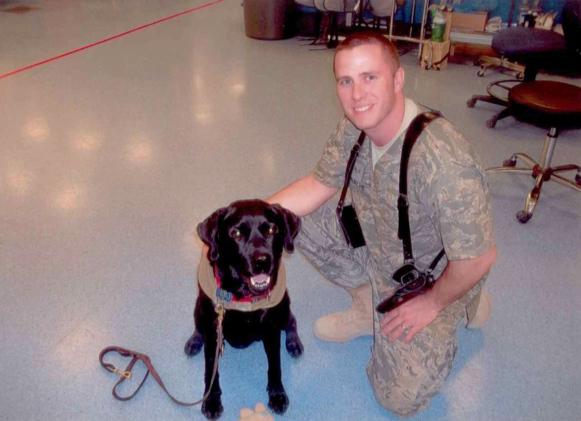 Senior Airman Justin Peattie visits with Zeke, a morale dog, during one of the dog’s visits to the trauma bay of the Role III Multinational Medical Unit at Kandahar Airfield, Afghanistan. Zeke visited every week and was a source of morale when times were tough for many patients. (Courtesy photo)