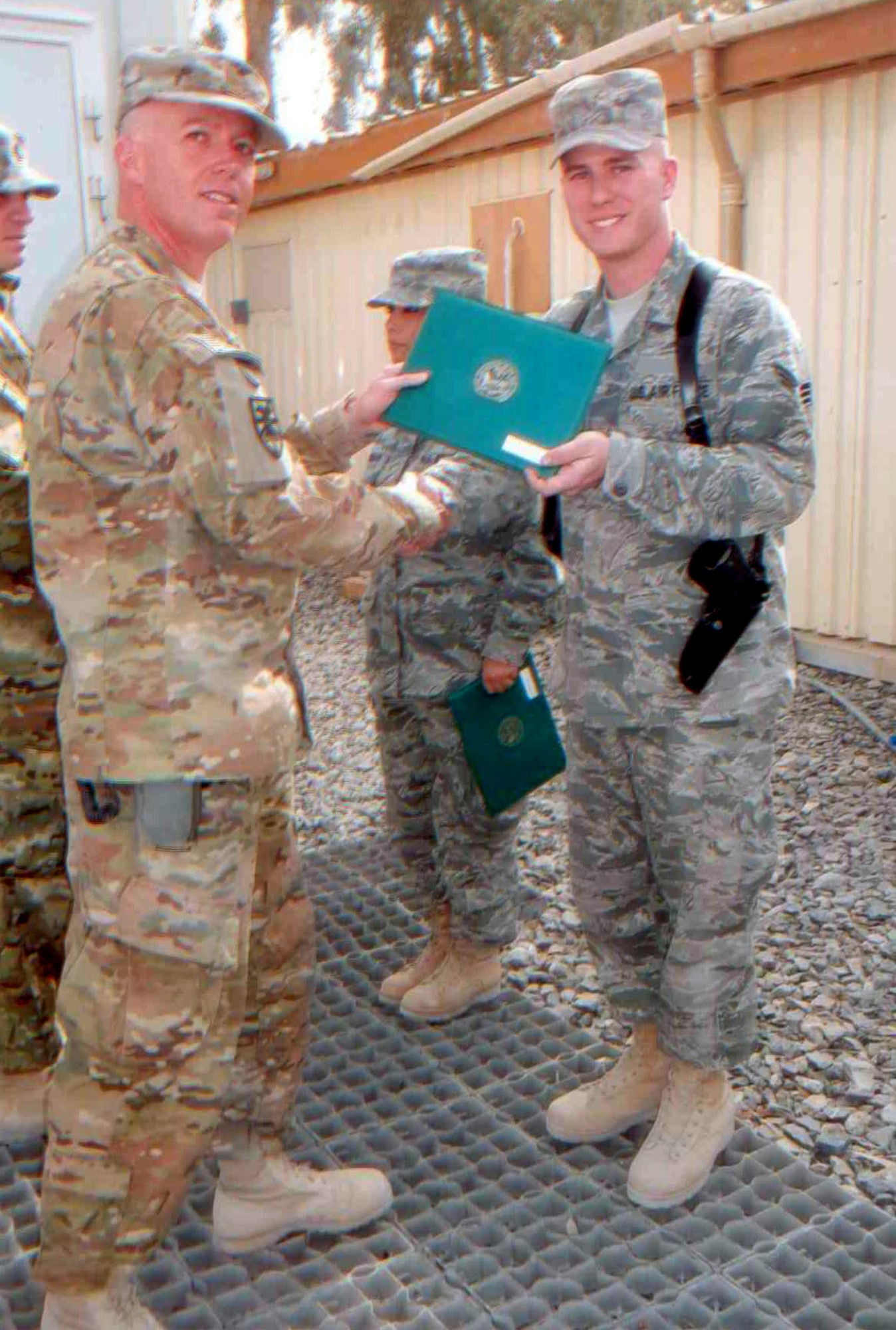 Senior Airman Justin Peattie accepts his Army achievement medal from Battalion Commander Maj. Stephen Cone prior to his departure from Kandahar Airfield, Afghanistan. Peattie served in a Joint Expeditionary Tasking assignment at the Role III Multinational Medical Unit as a as a member of the Casualty Liaison Team. (Courtesy photo)