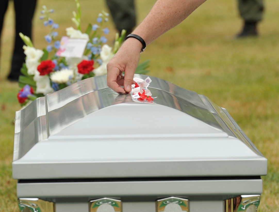 A family member lays a flower on a casket July 9 at Arlington National Cemetery in Arlington, Va. The remains of the six Airmen who went missing when their Douglas AC-47 Spooky gunship crashed in Laos on Christmas Eve 1965 during a Vietnam combat mission, were buried in Arlington after being identified through dental records, personal items and other circumstantial evidence. (U.S. Air Force photo/Senior Airman Perry Aston)