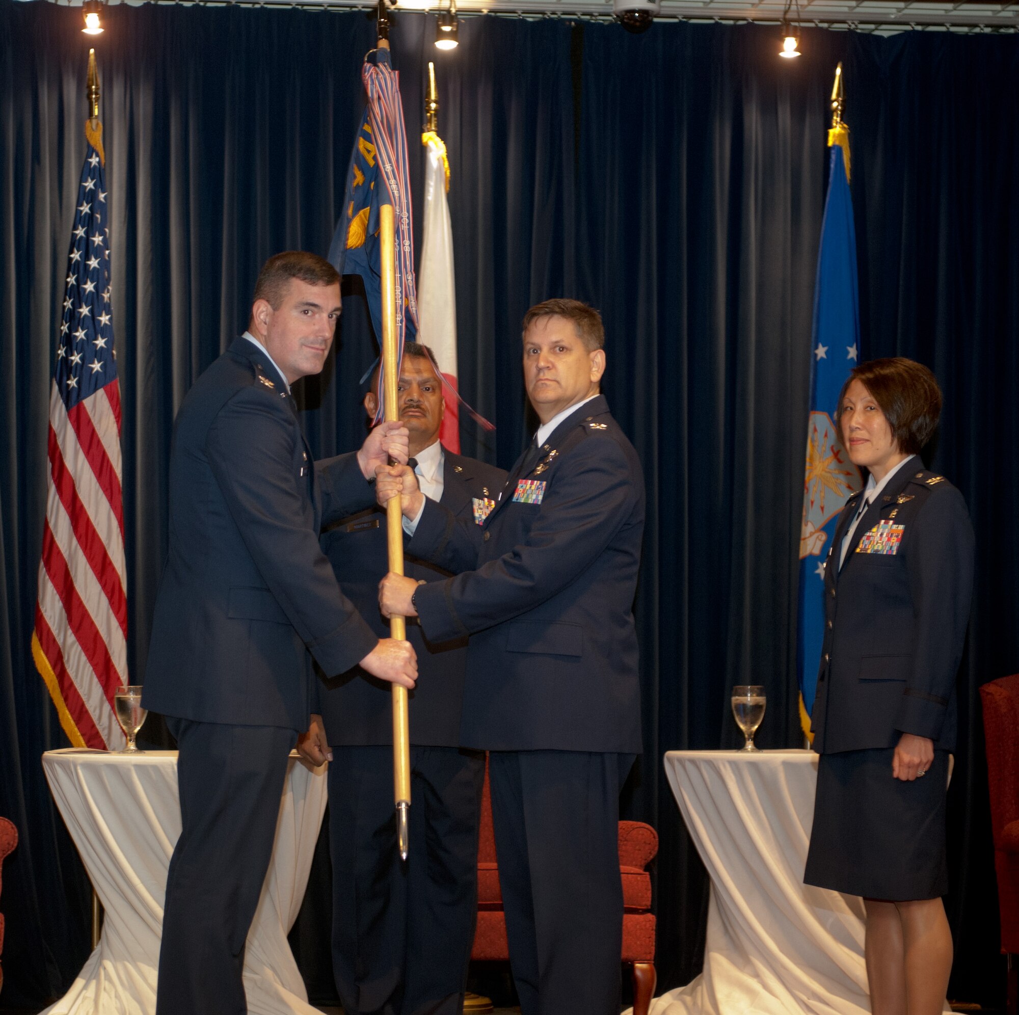 YOKOTA AIR BASE, Japan -- Col. Lee Harvis, 374th Medical Group outgoing commander, center, hands the group guidon to Col. Mark August, 374th Airlift Wing commander, left, during a change of command ceremony at Yokota Air Base, Japan, July 9, 2012. The guidon is a tradition dating back to Roman times, where military units would carry a banner with their emblem into battle. (U.S. Air Force photo by Airman 1st Class John D. Partlow)