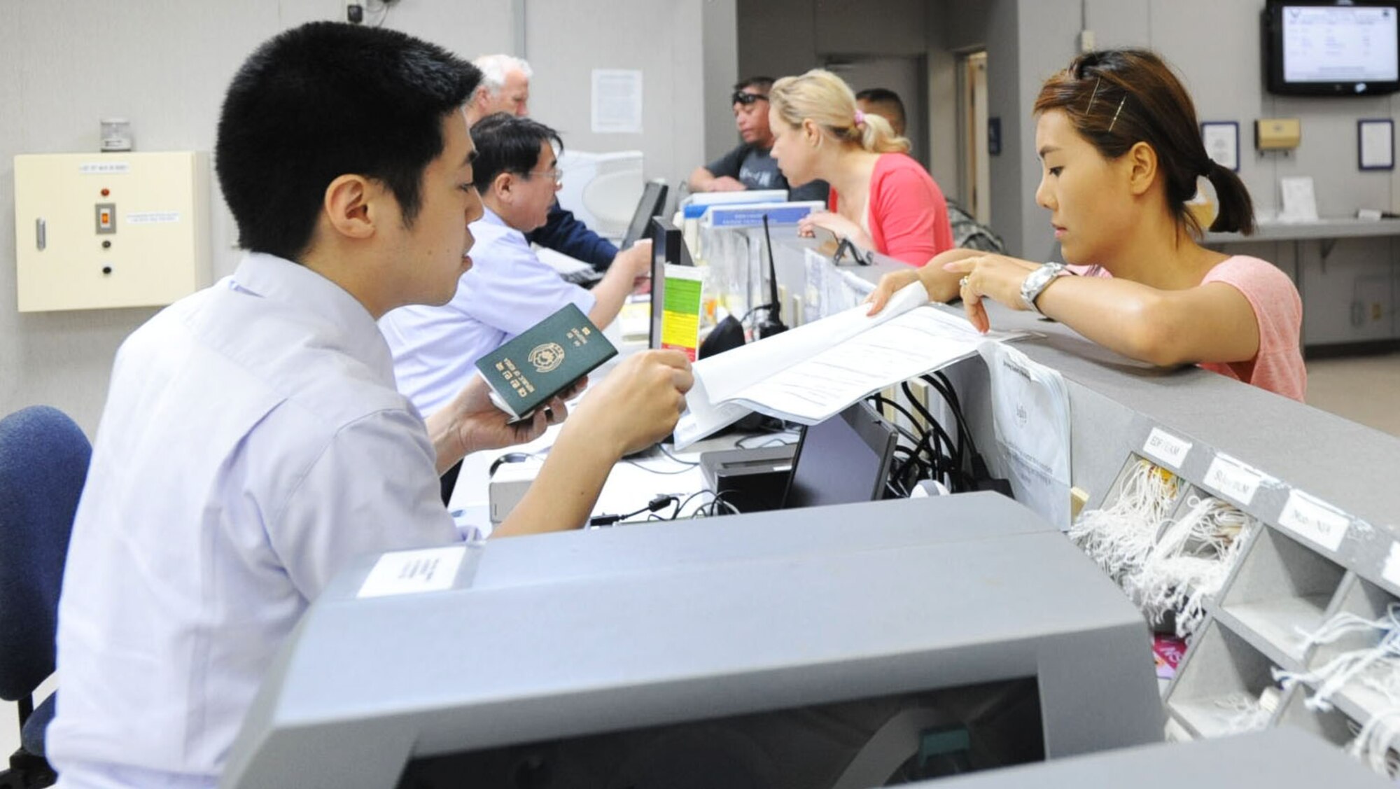 Shinya Nakano, left, Japanese immigration inspector, checks a traveler’s documents and passport before she leaves the country at Misawa Air Base, Japan, July 10, 2012. Non-Status of Forces Agreement travelers must have their passports stamped by Japanese Immigration Customs personnel before leaving the country or they will not be allowed to leave. (U.S. Air Force photo by Airman 1st Class Kenna Jackson/Released)