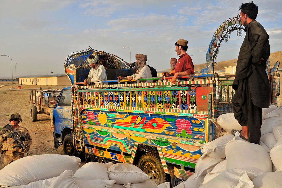 U.S. Army Spc. Nathan Smith, lower left, provides security while Afghan truck drivers pause after unloading bags of grain from a jingle truck during Operation Buffalo Thunder II at the district center in Shorabak, Afghanistan, June 30, 2012. Smith, an infantryman, is assigned to the 2nd Infantry Division's 1st Battalion, 17th Infantry Regiment. 