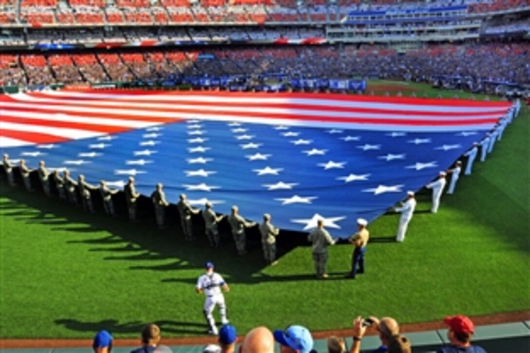 Sailors and airmen present a giant American flag before the 2012 major league baseball All-Star Game in Kansas City, Mo., July 10, 2012. The sailors are assigned to Navy Recruiting District Saint Louis and the Navy Operational Support Center, Kansas City, and the airmen are assigned to Whitman Air Force Base. More than 30 sailors and 45 airman held the flag during the singing of the national anthem and pregame events.