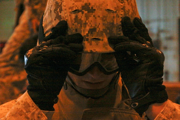 Lance Cpl. Casey J. Woerpel, station Installation Personnel Adiminstration Center travel claims clerk, pulls his goggles over his eyes before entering the Humvee Egress Assistance Trainer here July 11, 2012. The HEAT simulator trains Marines in the situation of a Humvee rolling over, which occurs when a top-heavy load, improvised explosive device or unfavorable road and weather conditions flip a Humvee.