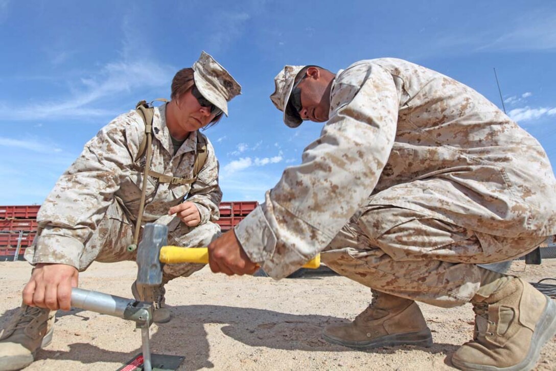 Sgt. Patricia L. Reynolds holds a stake in place for Pfc. Kenneth Gonzales during Large Scale Exercise-1, Javelin Thrust 2012, July 10. Both are radio operators with 9th Communication Battalion. Javelin Thrust is an annual exercise with 1st Marine Expeditionary Brigade at Marine Corps Air Ground Combat Center Twentynine Palms, Calif., which allows active and reserve Marines and sailors from 38 states to train together as a seamless Marine air-ground task force.