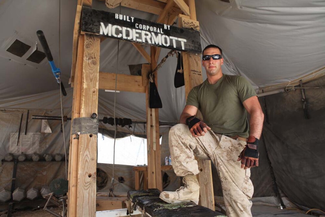 Corporal Frank McDermott, poses for a photo, July 7, 2012, by some of the gym equipment he built during his downtime in Afghanistan. Mcdermott, of Deleran, N.J., used his hobby of building things to help his hobby of working out.