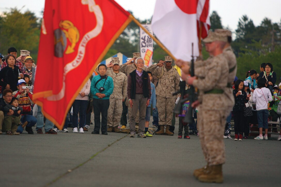 A Marine color guard salutes the playing of the Japanese and American national anthems during the opening ceremony of the Camp Fuji friendship festival at the Combined Arms Training Center Camp Fuji May 12. The festival provided an opportunity for the local community and the Marines to come together and celebrate the relationship fostered between them. 
