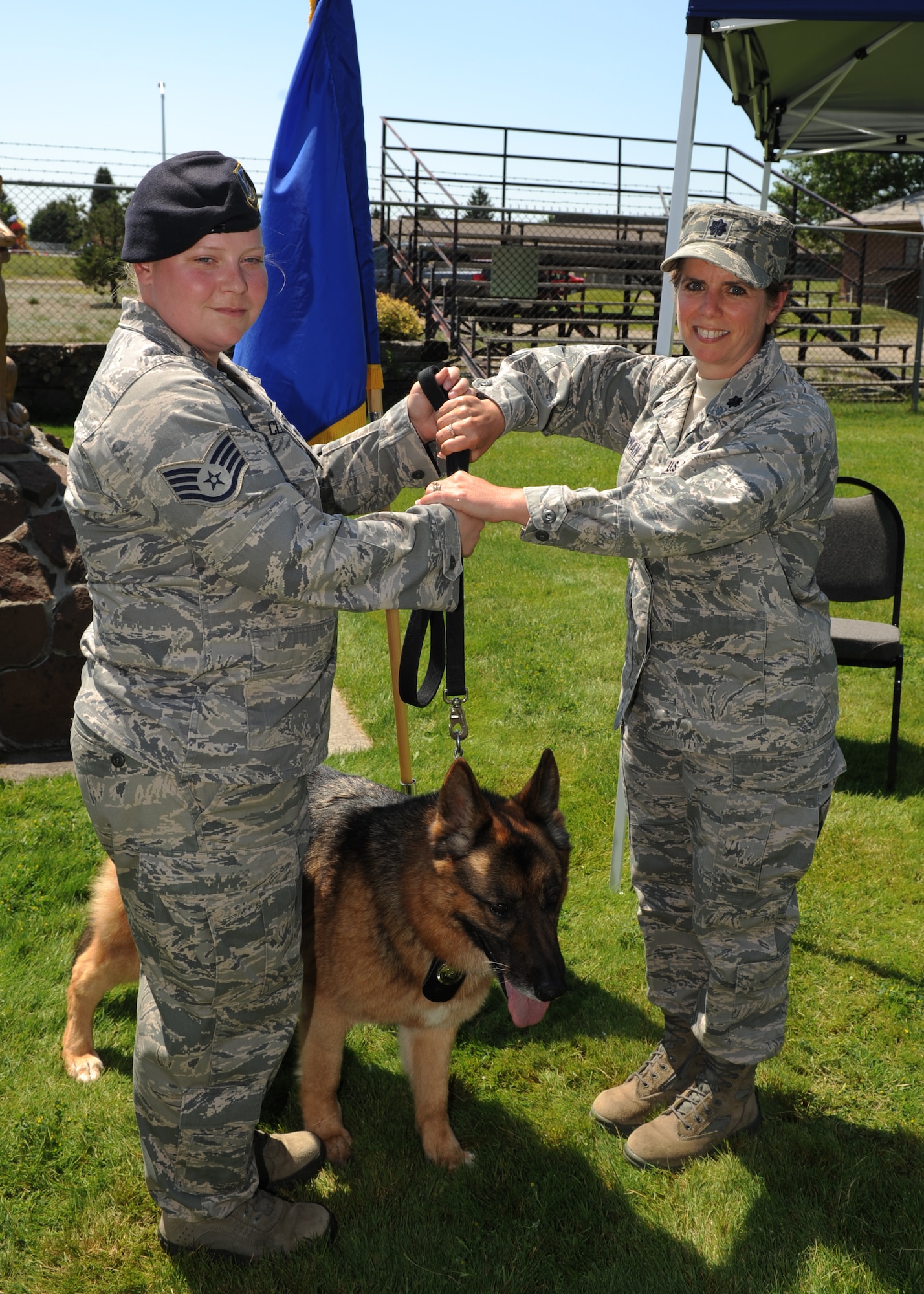 Staff Sgt Meredith Clement, 92nd Security Forces Squadron military working dog handler, relinquishes leash and absolute control of MWD Golf to Lt. Col. Wendy Sherman, 92nd Air Refueling Wing staff judge advocate, during a retirement ceremony at Fairchild Air Force Base, Wash., July 9, 2012. Golf served at Fairchild for nine years and has been adopted into Sherman's family as a household companion. (U.S Air Force photo by Staff Sgt. Michael Means/Released)