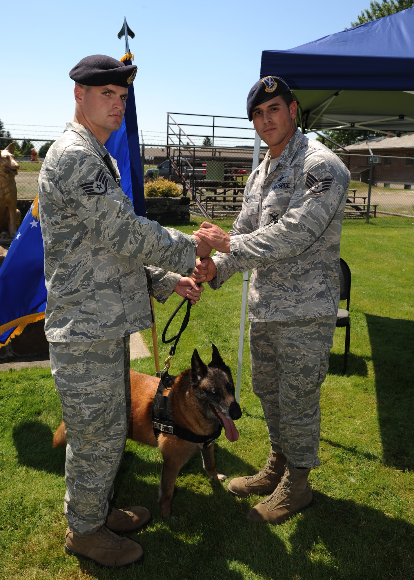 Staff Sgt. David Newell, 92nd Security Forces Squadron military working dog handler, relinquishes the leash and absolute control of MWD Dakota to Staff Sgt. Jose Cadena, 92nd SFS commander, during a retirement ceremony at Fairchild Air Force Base, Wash., July 9, 2012. Cadena and Dakota have delpoyed together twice and have built a strong bond during their time together. (U.S Air Force photo by Staff Sgt. Michael Means/Released)