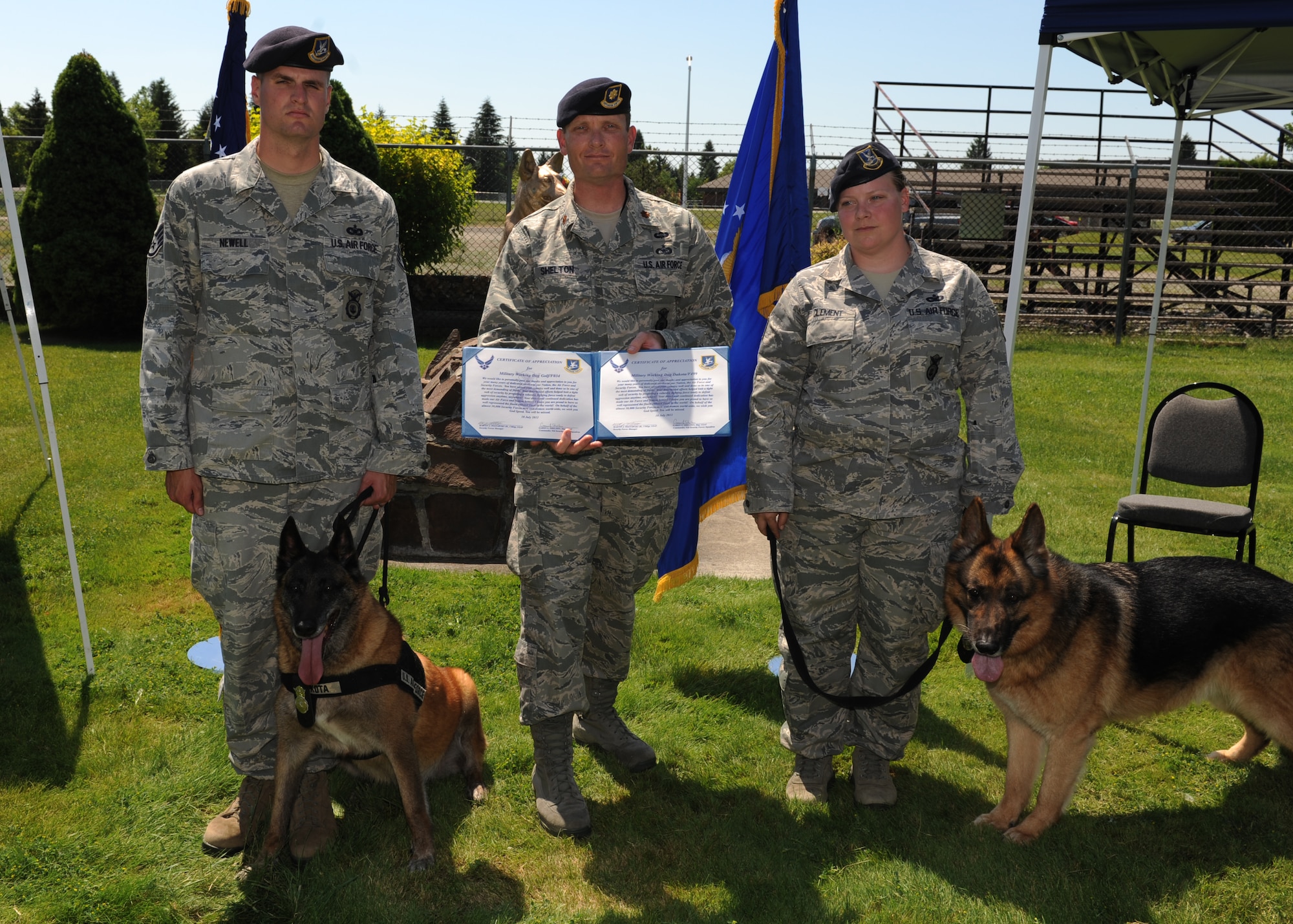 Maj. Garon Shelton, 92nd Security Forces Squadron commander, holds a certificate of appreciation, presented to Military Working Dogs Dakota and Golf at a retirement ceremony in honor of their service at Fairchild Air Force Base, Wash., July 9, 2012. Dakota, assigned to Fairchild for eight years, and Golf, assigned to Fairchild for nine, were both recognized for their long list of achievements while serving in the military. (U.S Air Force photo by Staff Sgt. Michael Means/Released)