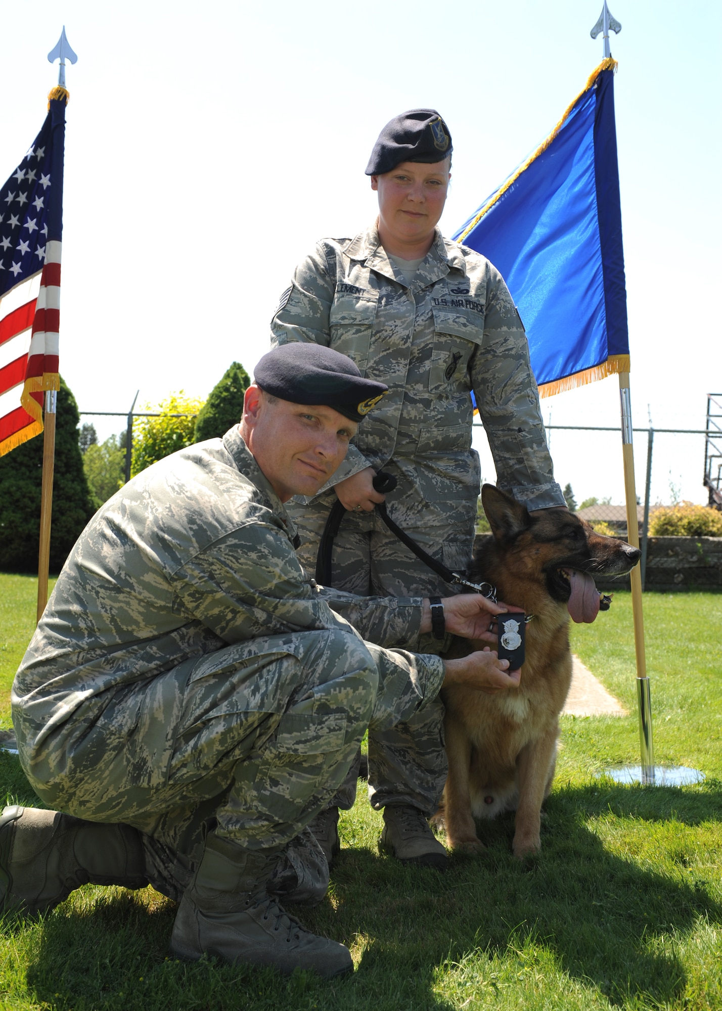 Maj. Garon Shelton, 92nd Security Forces Squadron commander, pins the Sercurity Forces shield on Military Working Dog Golf, escorted by Staff Sgt. Meredith Clement, 92nd SFS MWD handler, during a retirement ceremony at Fairchild Air Force Base, Wash., July 9, 2012. Golf has deployed in support and Operations Iraqi Freedom and Enduring Freedom as well as provided support to the United States Customs and Border Protection. (U.S Air Force photo by Staff Sgt. Michael Means/Released)