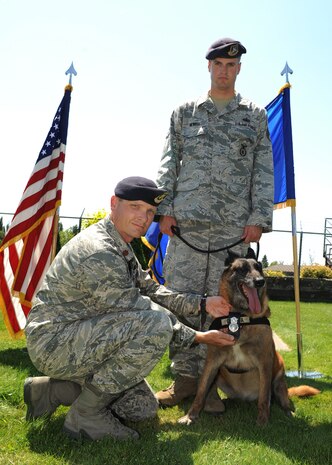 Maj. Garon Shelton, 92nd Security Forces Squadron commander, pins the Sercurity Forces shield on Military Working Dog Dakota, escorted by Staff Sgt. David Newell, 92nd SFS MWD handler, at a retirement ceremony in honor of Dakota at Fairchild Air Force Base, Wash., July 9, 2012. Dakota served as an Explosive Detector Dog and has deployed six times as well as provide support for multiple missions with the U.S. Secret Service, coalition and mulitnational forces. (U.S Air Force photo by Staff Sgt. Michael Means/Released)