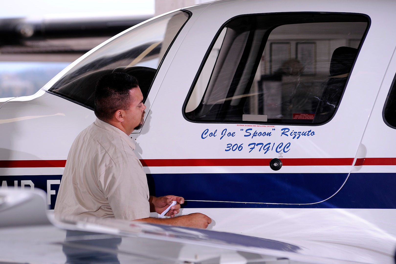 A Doss Aviation employee unveils Col. Joseph Rizzuto’s name on the side of a T-53A, the military variant of the Cirrus SR-20. Rizzuto took command of the 306th Flying Training Group in a change of command ceremony July 9. Rizzuto comes to the Academy from Maxwell Air Force Base, Ala. (U.S. Air Force Photo/Mike Kaplan)