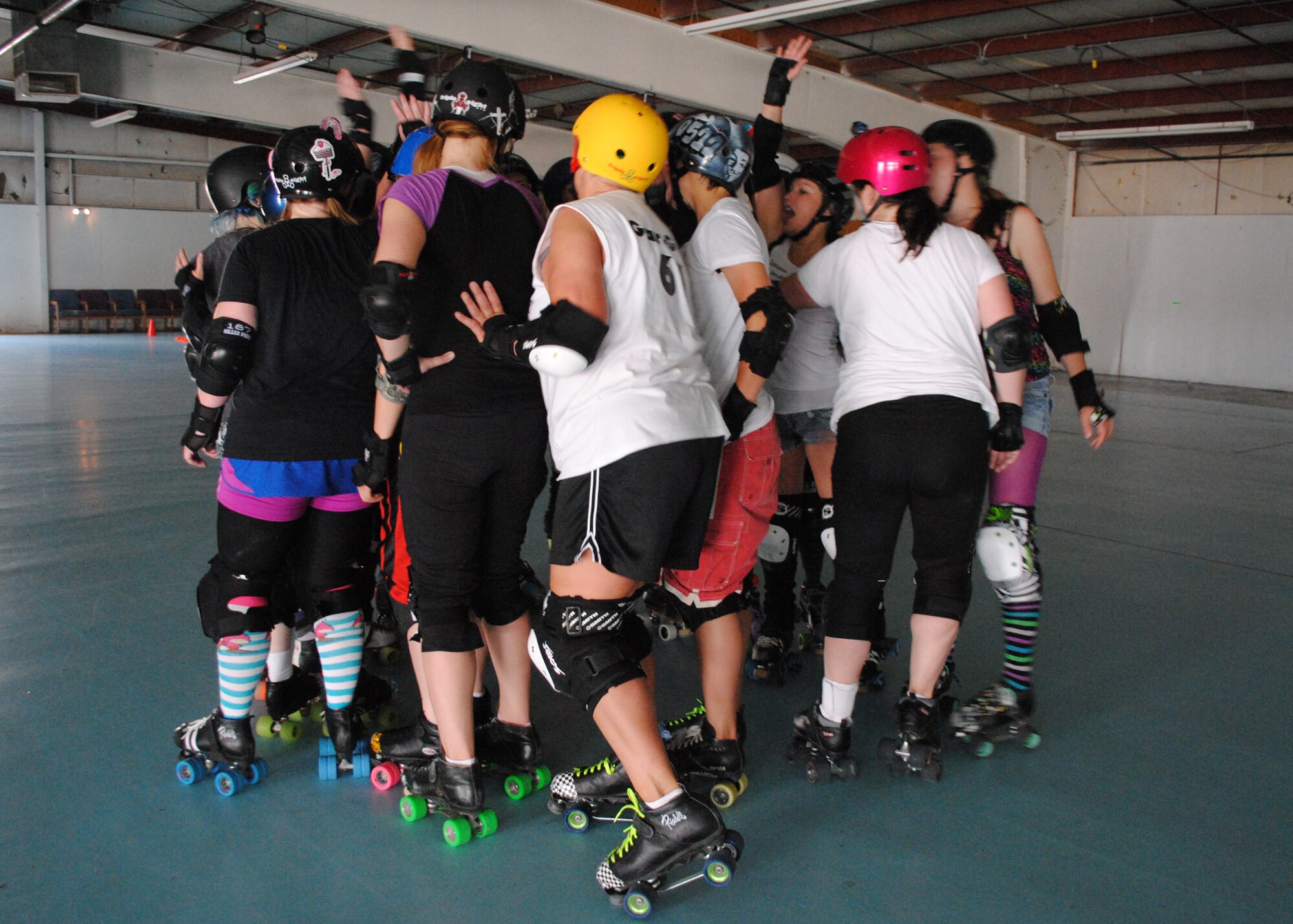 Members of the Great Falls Electric City Roller GrrrlZ team put their hands together and pump each other up with words of encouragement at the end of practice. (U.S. Air Force photo/Airman 1st Class Katrina Heikkinen)