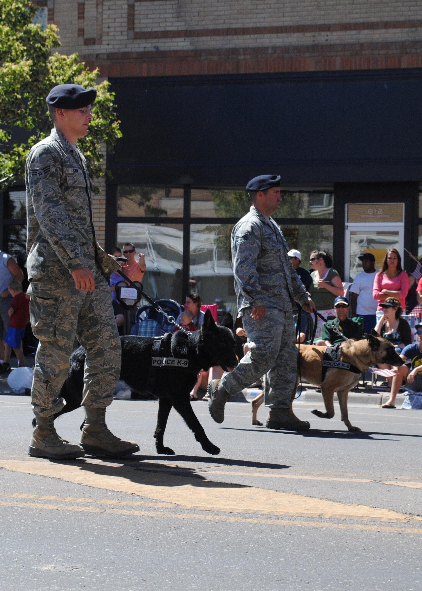 Senior Airman Dustin Cain, 341st Security Forces Squadron K-9 handler (left), walking with Suzy, a 4-year-old German shepherd, and Staff Sgt. Samuel Enrico, 341st SFS K-9 handler, walking with Tom, a 4-year-old Belgian Malinois, participate in the parade in downtown Great Falls July 4.  Thousands of people attended the parade, which held several displays of local military personnel and equipment as well as other freedom-inspired floats.  (U.S. Air Force photo/Airman 1st Class Cortney Paxton)