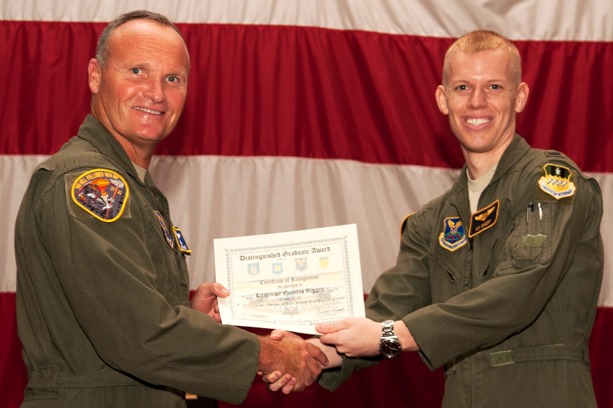 U.S. Air Force Brig. Gen. James Brown, Air Force Global Strike Command director of operations, presents the Electronic Warfare Officer Distinguished Graduate certificate to 1st Lt. Nicholas Biggert during a graduation ceremony on Barksdale Air Force Base, La., July 10, 2012. The Distinguished Graduate Award is given to the student who has demonstrated at least a 90 percent average in all areas of training and performance that was consistently and clearly above his peers. (U.S. Air Force photo by Master Sgt. Greg Steele/Released)