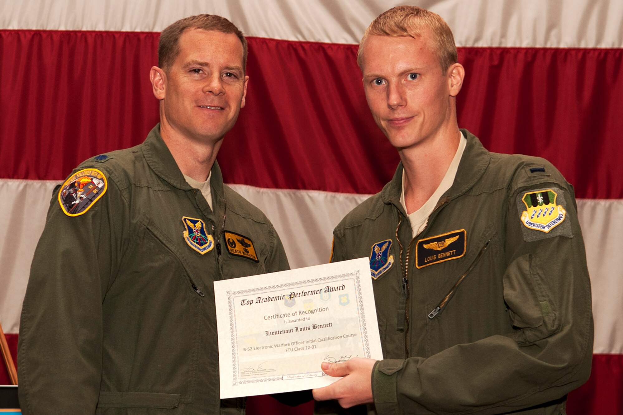U.S. Air Force Lt. Col. William Wharton, 11th Bomb Squadron commander, presents the Electronic Warfare Officer Outstanding Academic Performer certificate to 1st Lt. Louis Bennett during a graduation ceremony on Barksdale Air Force Base, La., July 10, 2012. Bennett graduated from the Formal Training Unit at Barksdale where he spent nine months learning to fly the B-52H Stratofortress and achieved an overall academic average of 99 percent. (U.S. Air Force photo by Master Sgt. Greg Steele/Released)