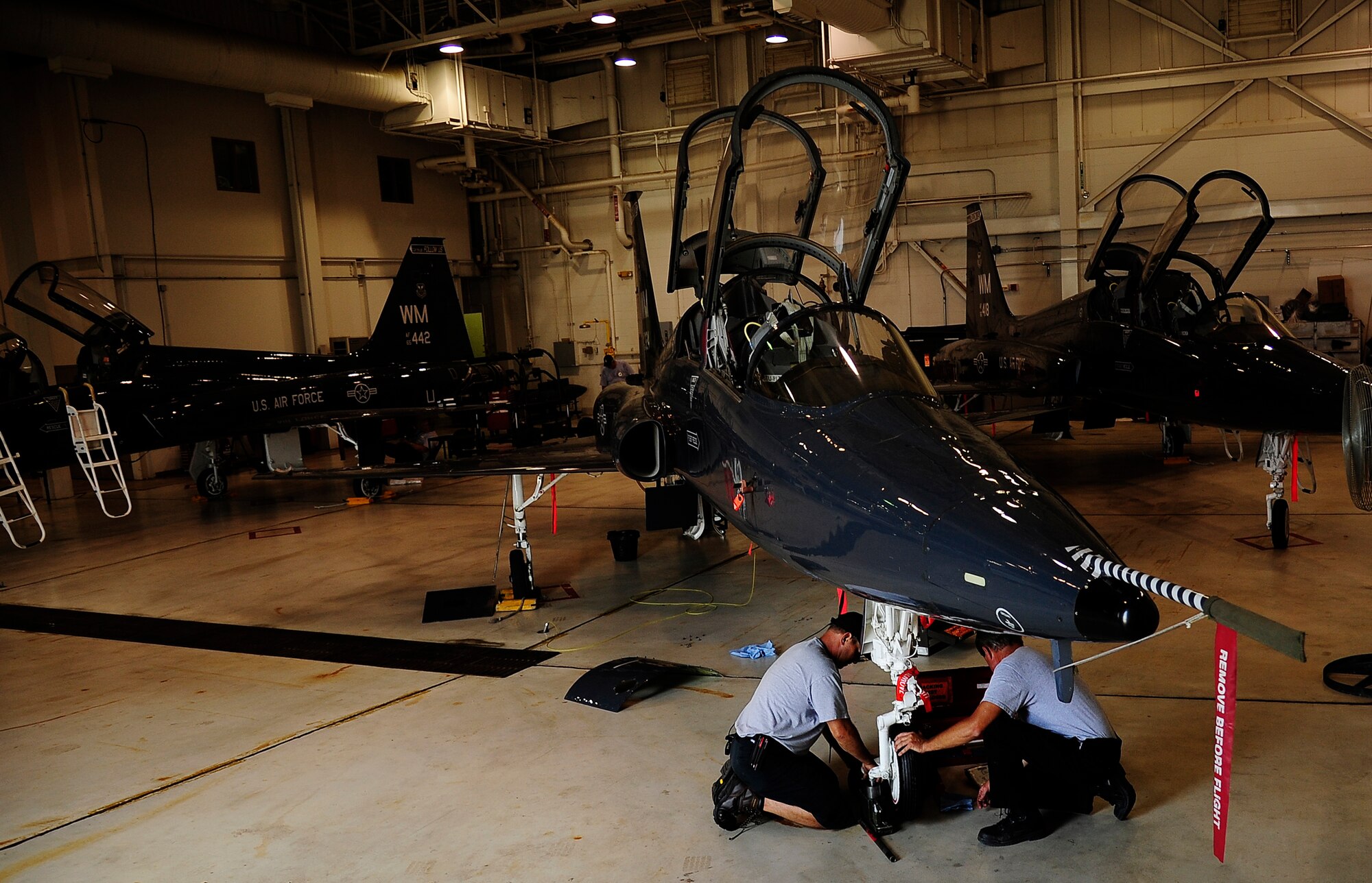 WHITEMAN AIR FORCE BASE, Mo. -- Jim Sales and Randy Tapley, M1 Support Services contractors, replace a T-38 Talon's nose gear tire and bearings during an Hourly postflight inspection here July 3. Keeping the Talon in the sky requires M1 employees to conduct a scheduled HPO inspection every 225 flight hours, including the aircraft's airframe gear mounted box's oil and filter replacement, checking the engine power packs for proper oil servicing and ensuring wing security. (U.S. Air Force photo/ Senior Airman Cody H. Ramirez)



