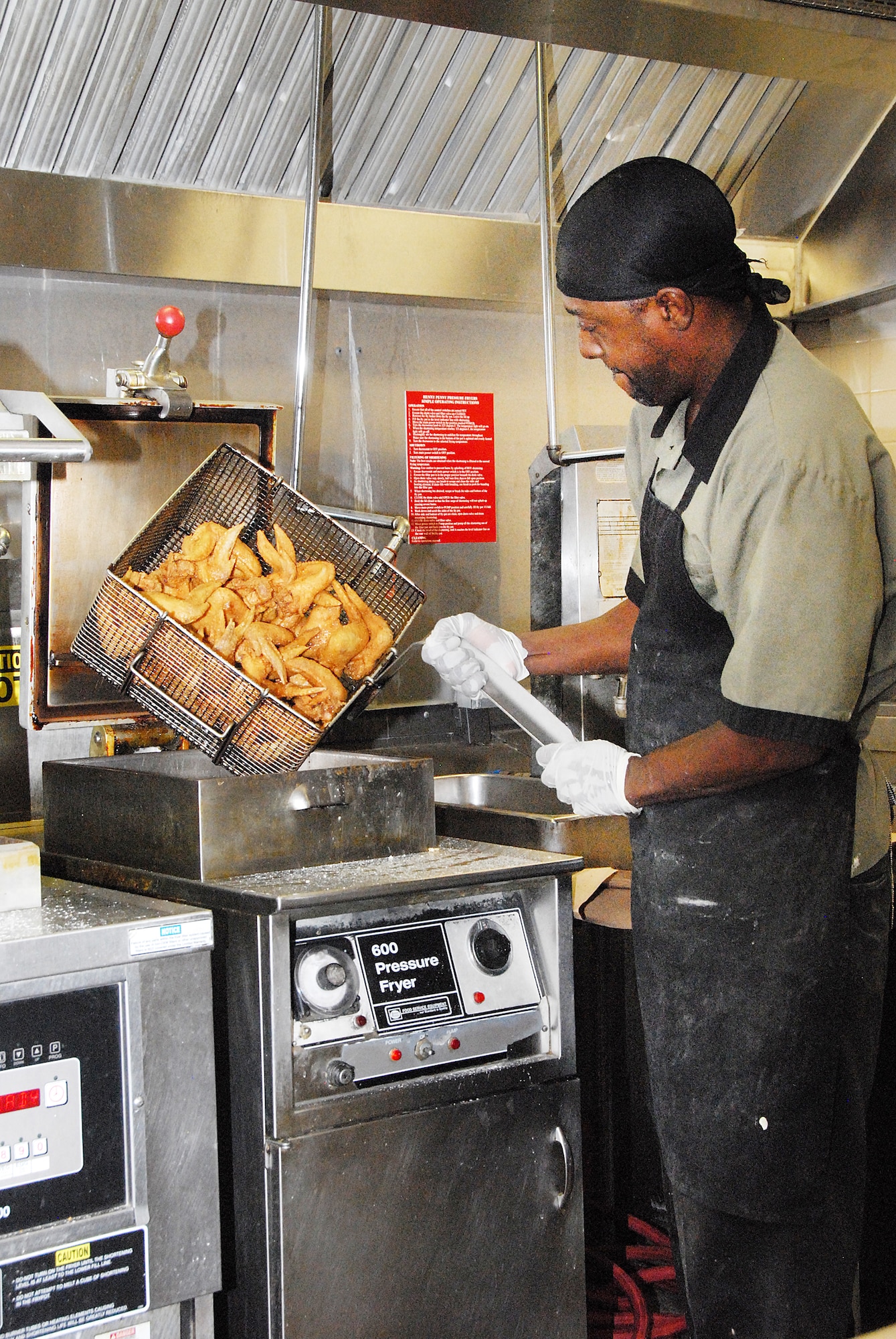 Anthony Nobles removes fried chicken from the deep fryer. Nobles said he may fry around 200 lbs of chicken to prepare for the lunch crowd.(U. S. Air Force photo/Misuzu Allen)