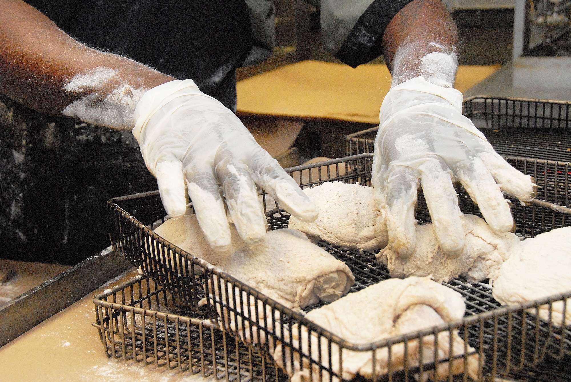 Anthony Nobles places battered chicken in a wire tray to go in the deep fryer.(U. S. Air Force photo/Misuzu Allen)