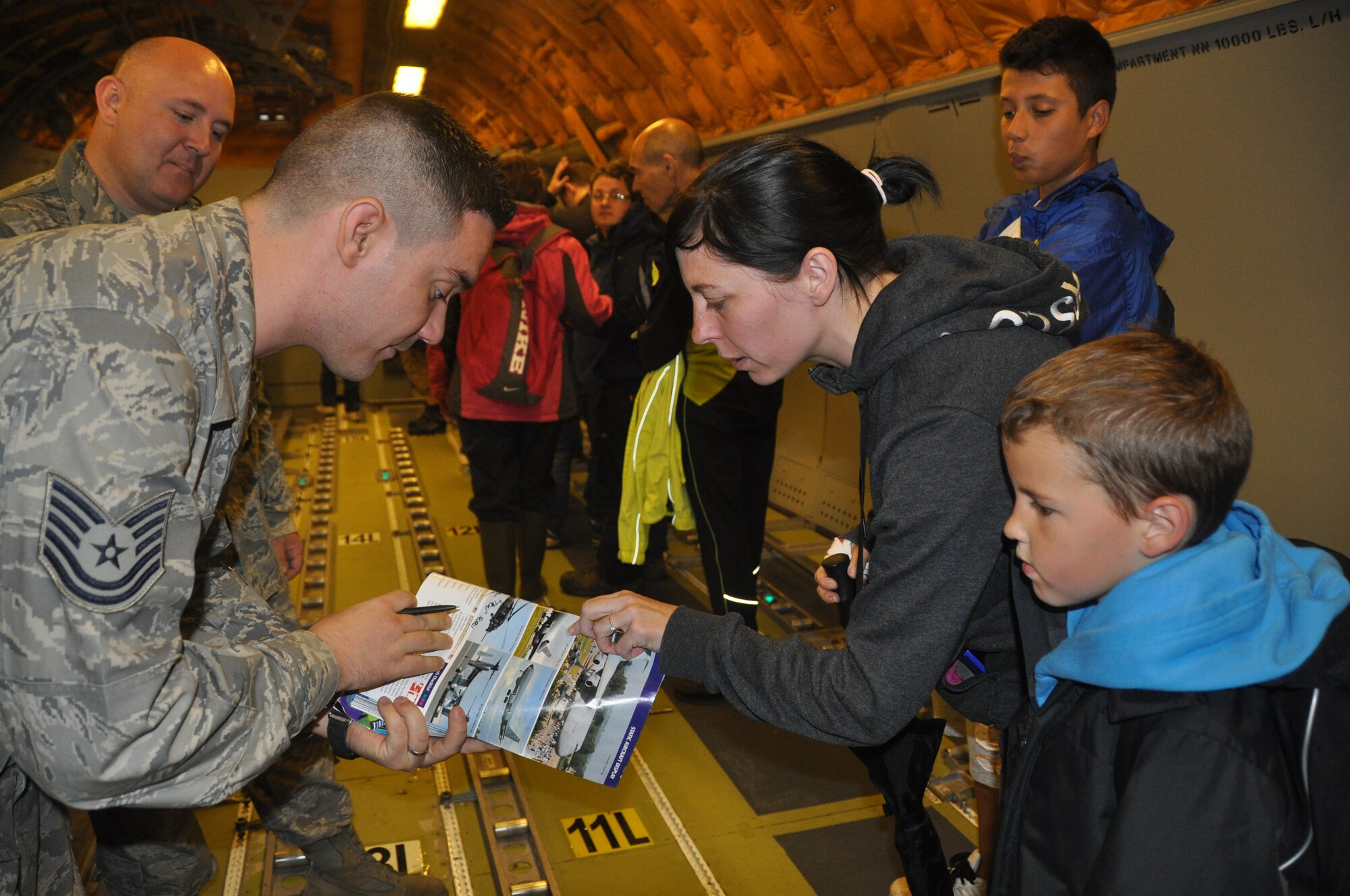 Tech. Sgt. Adam Ligon, a Reserve Airman assigned to Joint Base McGuire-Dix-Lakehurst in New Jersey, finds the correct photo to sign in the Royal International Air Tattoo souvenir book July 7. Thousands of air show spectators toured the KC-10 Extender during the annual event held at RAF Fairford in Gloucestershire, United Kingdom. (U.S. Air Force photo/Master Sgt. Donna T. Jeffries)
