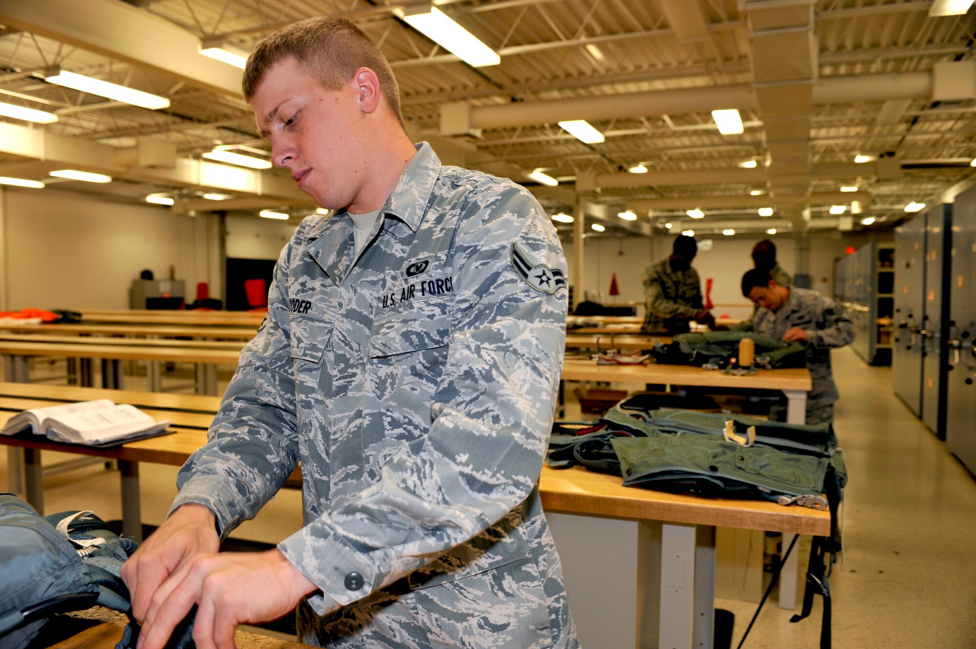 U.S. Air Force Airman 1st Class Josef Coder, 27th Special Operations Support Squadron aircrew flight equipment apprentice, repackages a parachute while working in the aircrew flight equipment shop at Cannon Air Force Base, N.M., July 9, 2012. This shop is responsible for maintaining all emergency flight equipment and training flight crew members in the use of these items. (U.S. Air Force photo by Airman 1st Class Ericka Engblom)