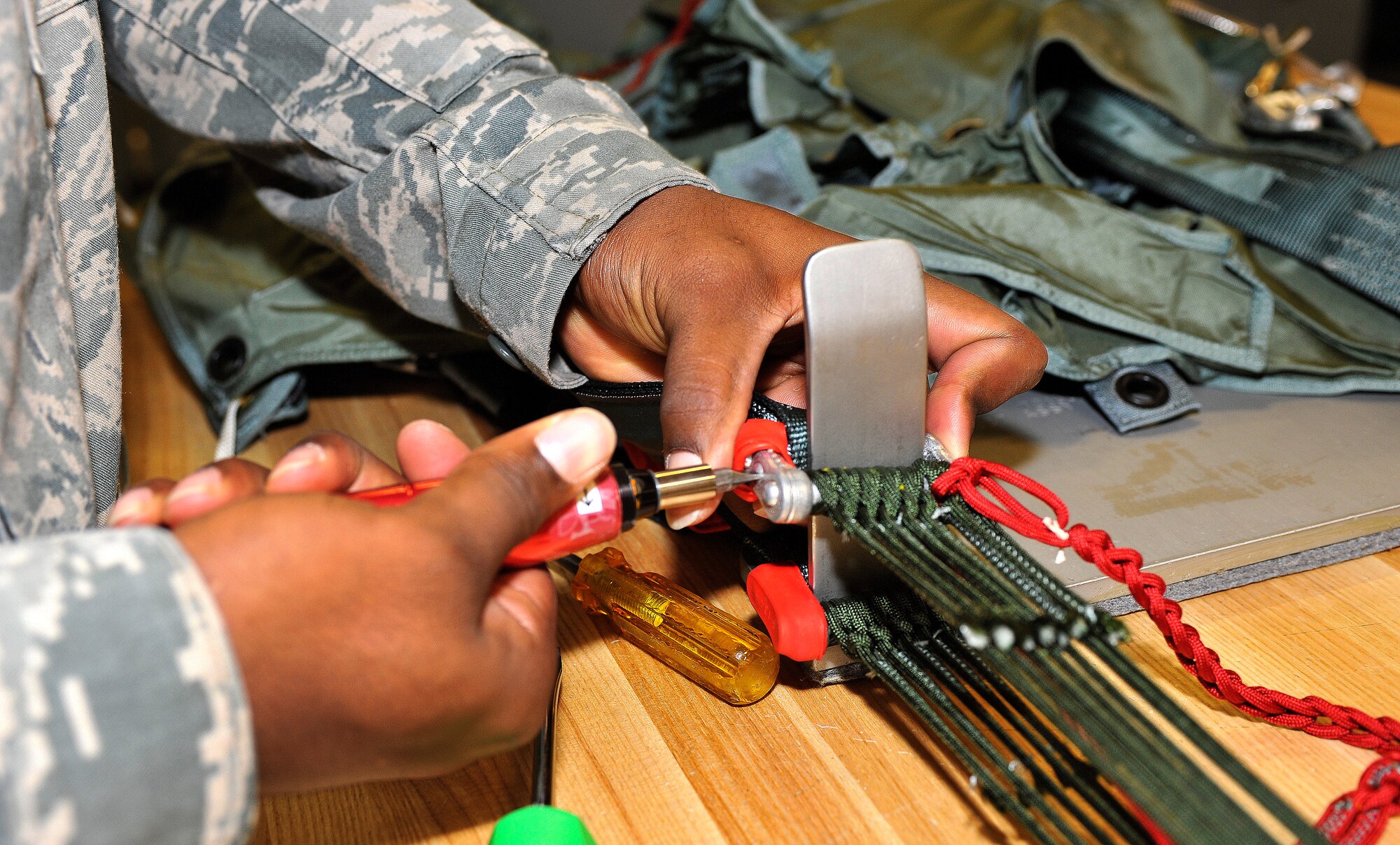 U.S. Air Force Airman 1st Class Zachary Smith, 27th Special Operations Support Squadron aircrew flight equipment apprentice, tightens a screw while repackaging a parachute at Cannon Air Force Base, N.M., July 9, 2012. Smith is a member of the aircrew flight equipment shop and assists with the repair and maintenance of emergency flight equipment. (U.S. Air Force photo by Airman 1st Class Ericka Engblom)